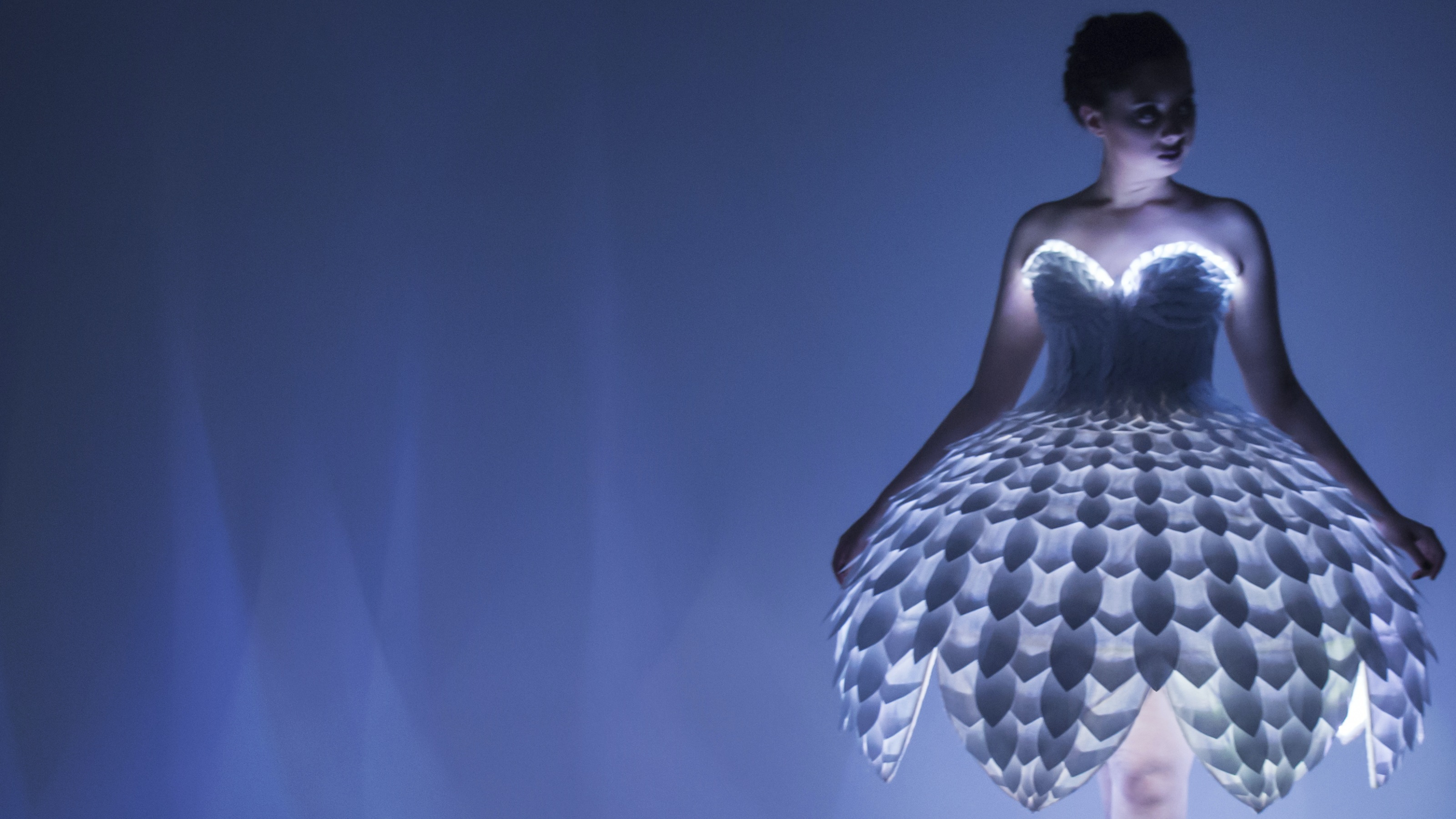 A ballerina in a luminous dress lit with blue fluorescent lighting