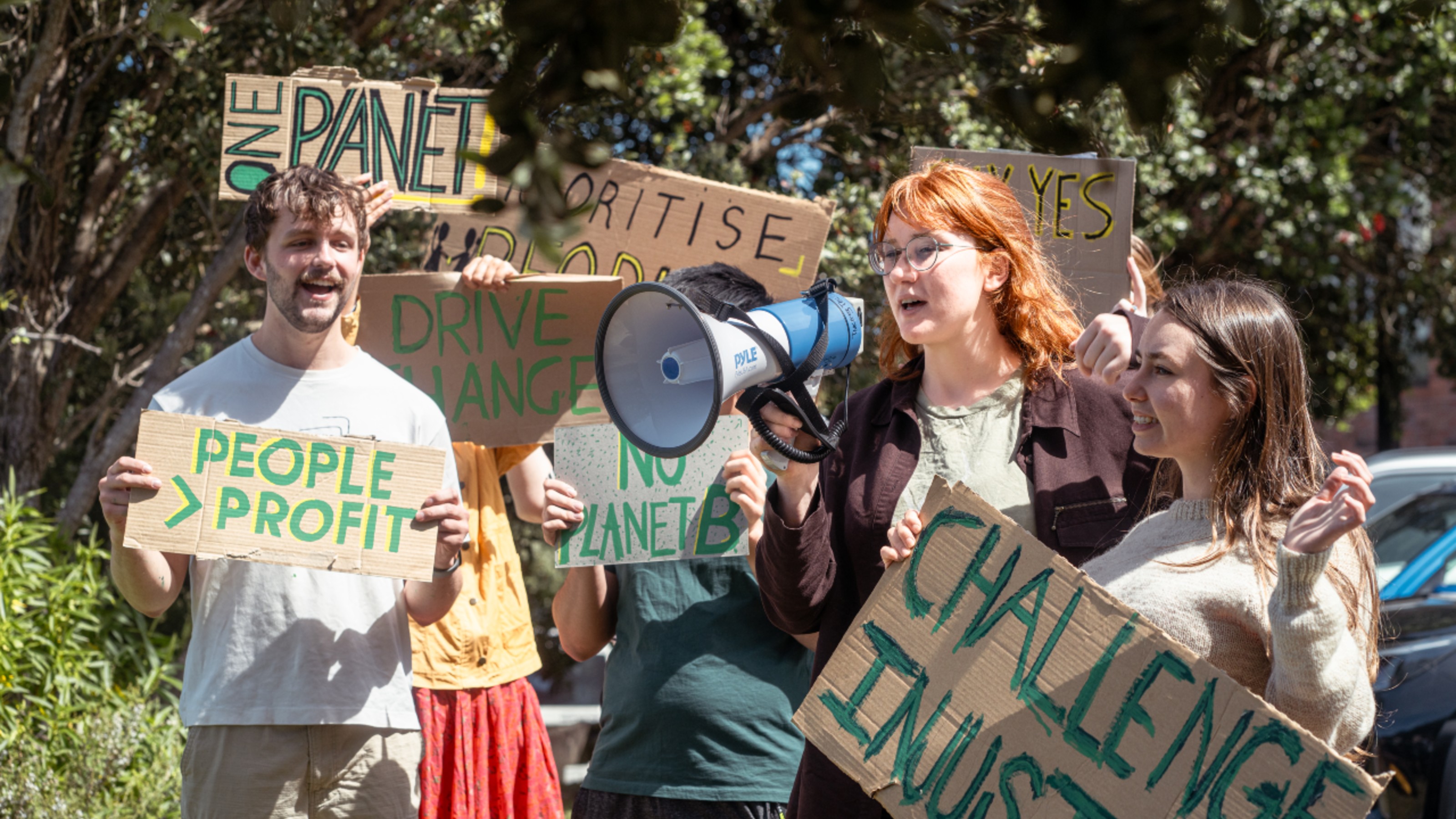 A group of students at a protest for movement on climate change, the students are a mix of feminine and masculine.