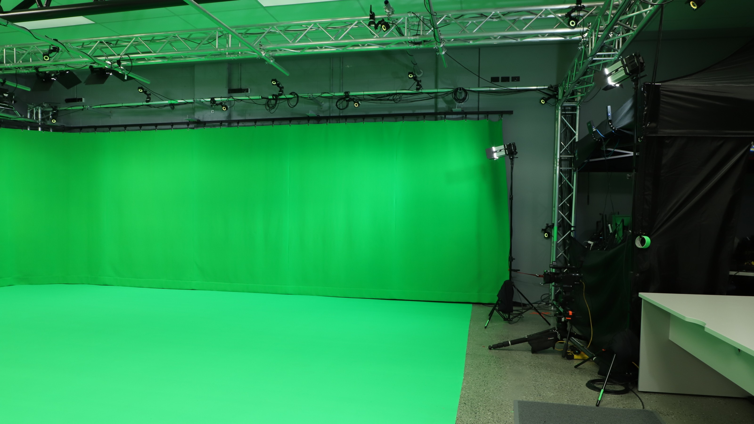 Studio with grey walls, green curtain, large screens.