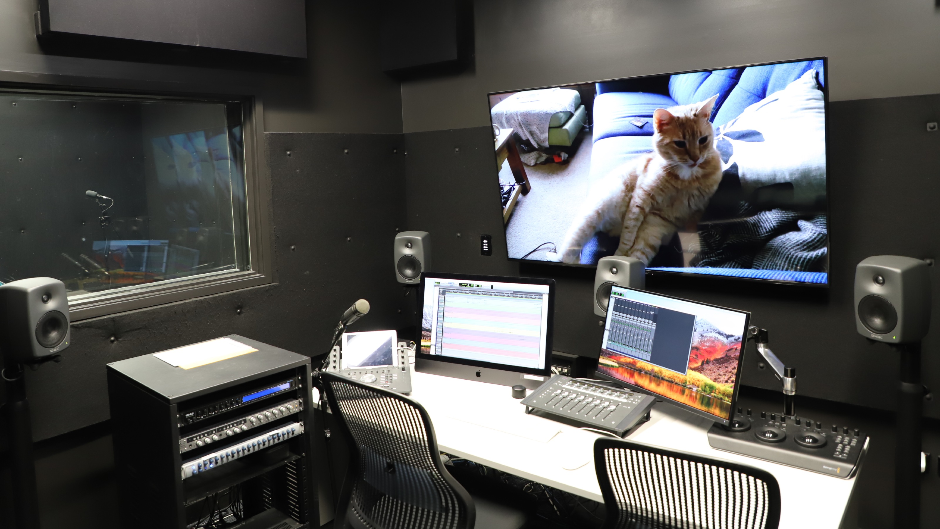 View of the editing suite with large screen, speakers, and technical material.