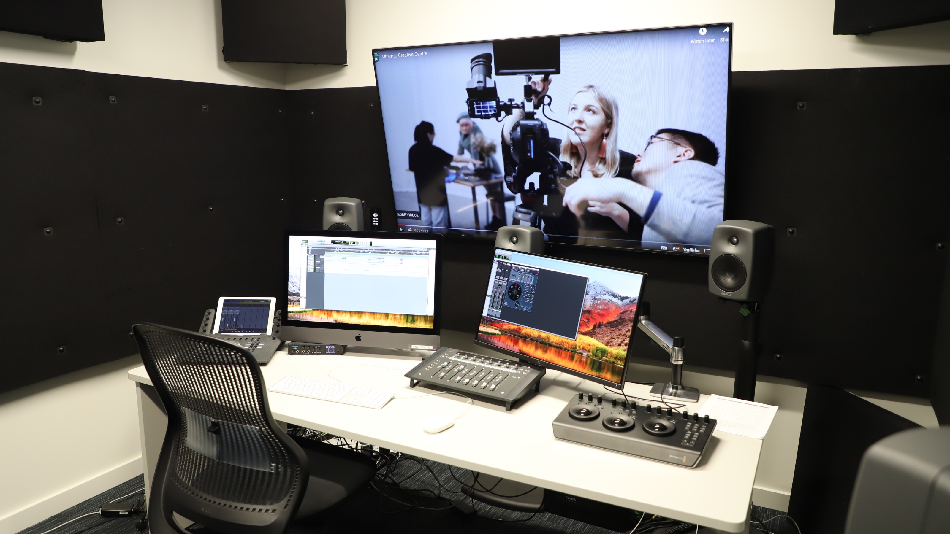 View of the editing suite with large screen, speakers, and technical material.