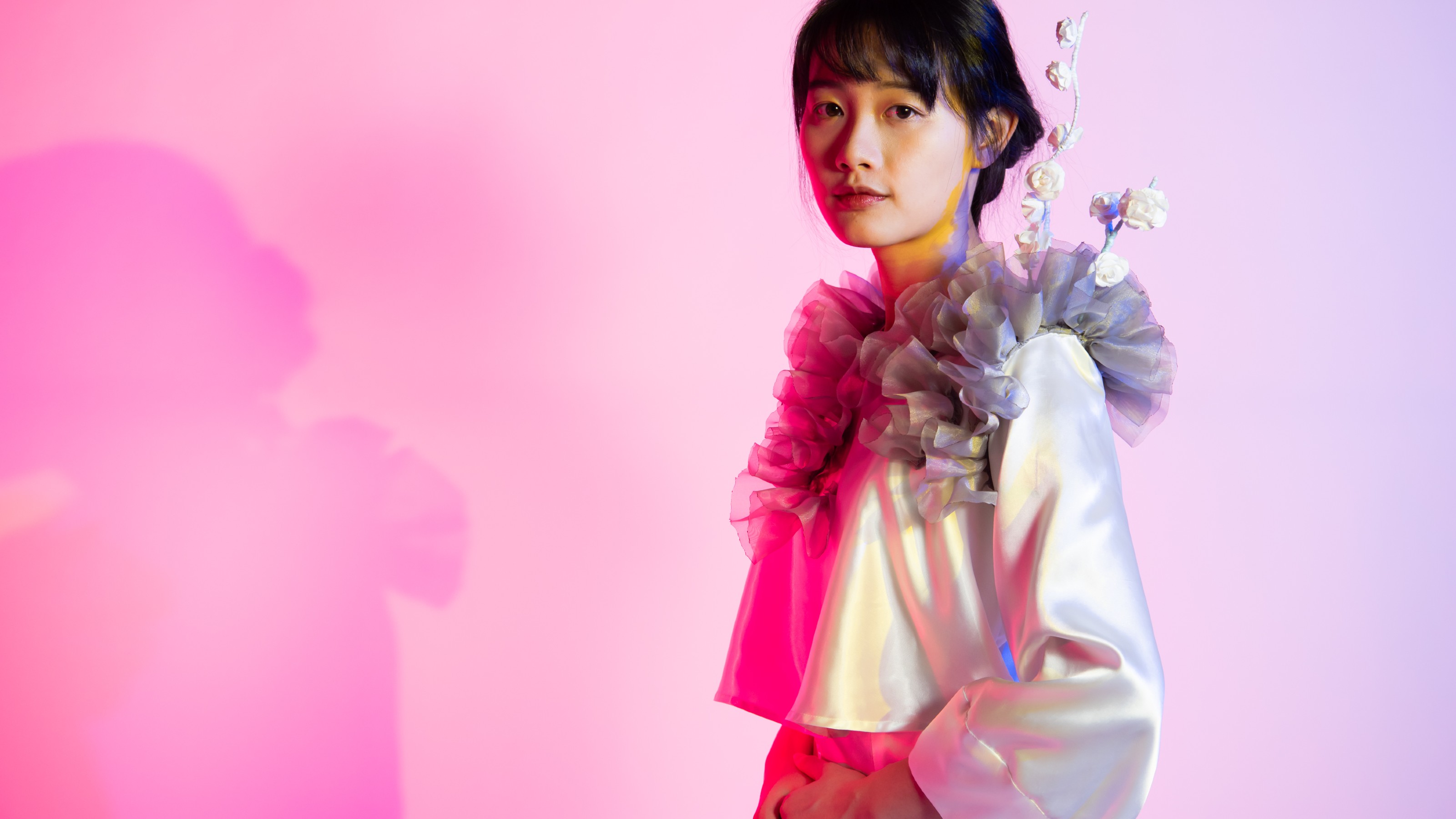 Model wearing a satin and silk organza-based dress shirt with ruffles and flowers on the shoulders and chest