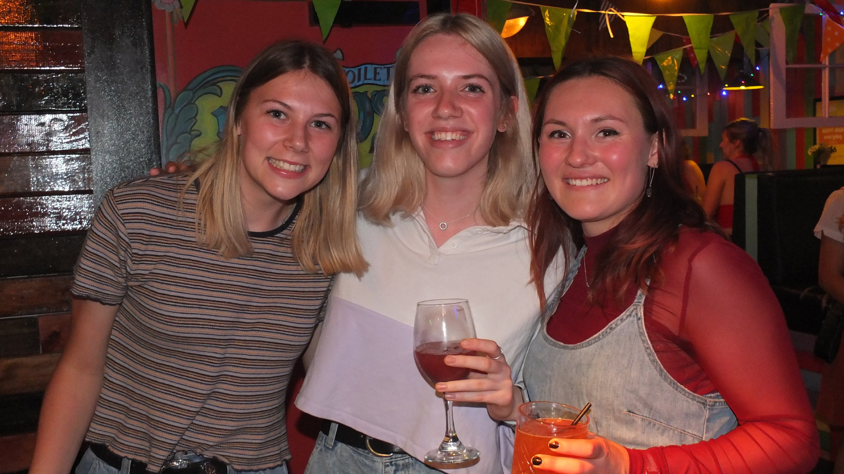 Three students with drinks at a social night.