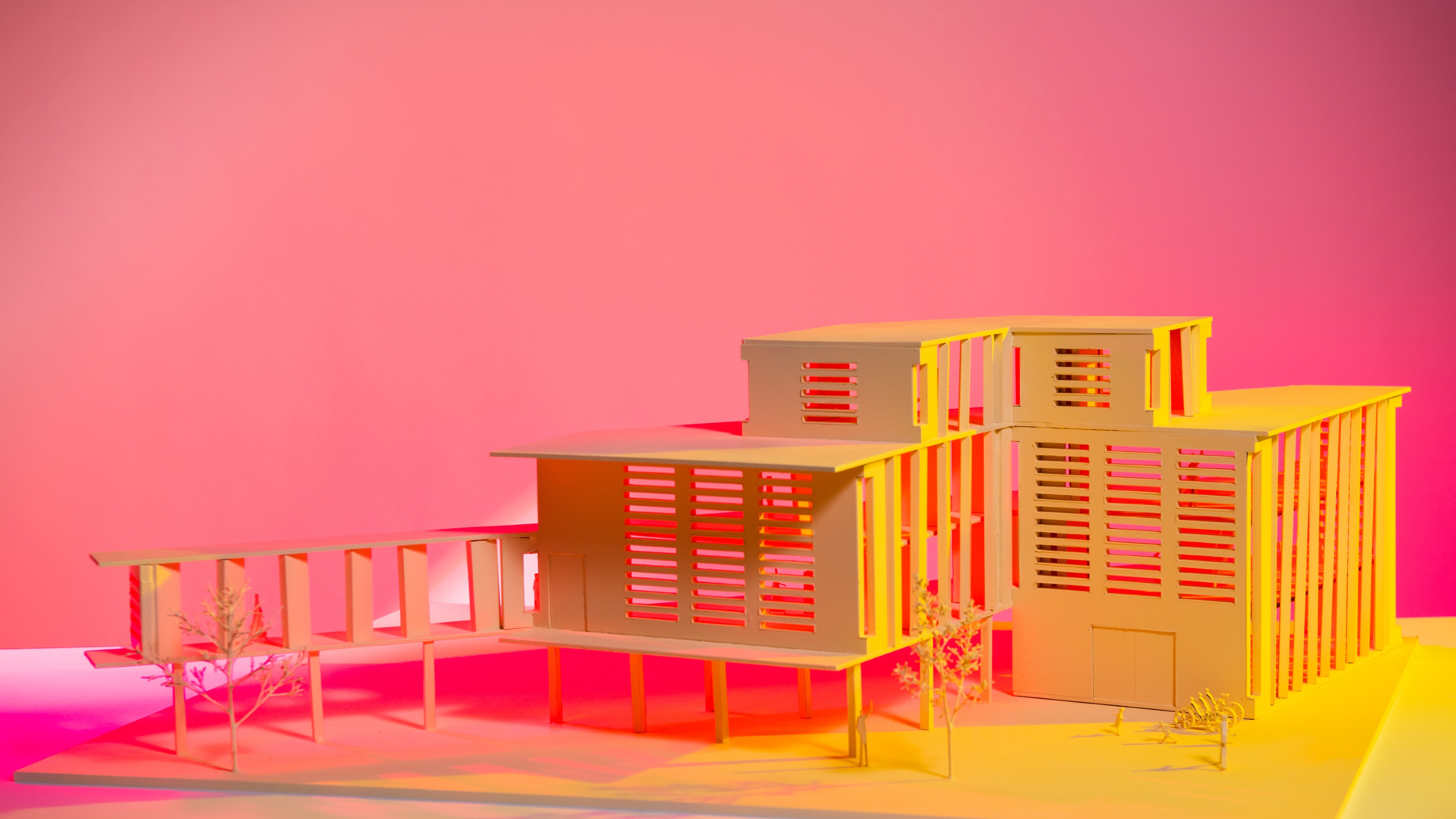 architectural model lit with yellow light in front of pink background