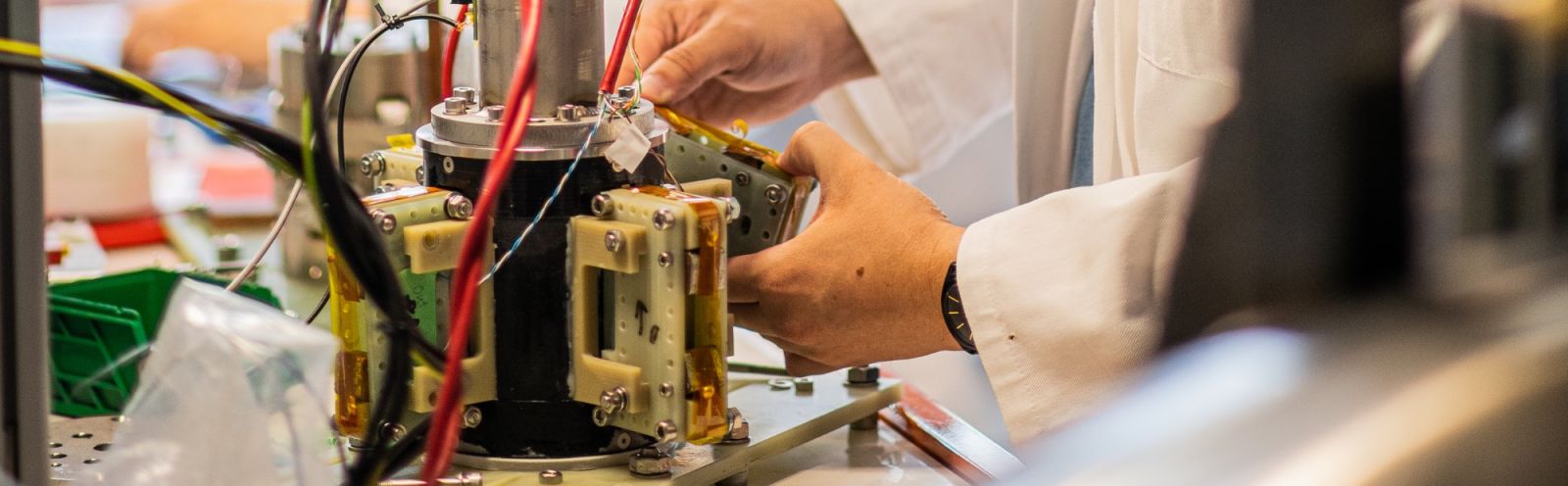 An experimental superconductor machine being adjusted by the hands of PhD student Ratu Mataira.