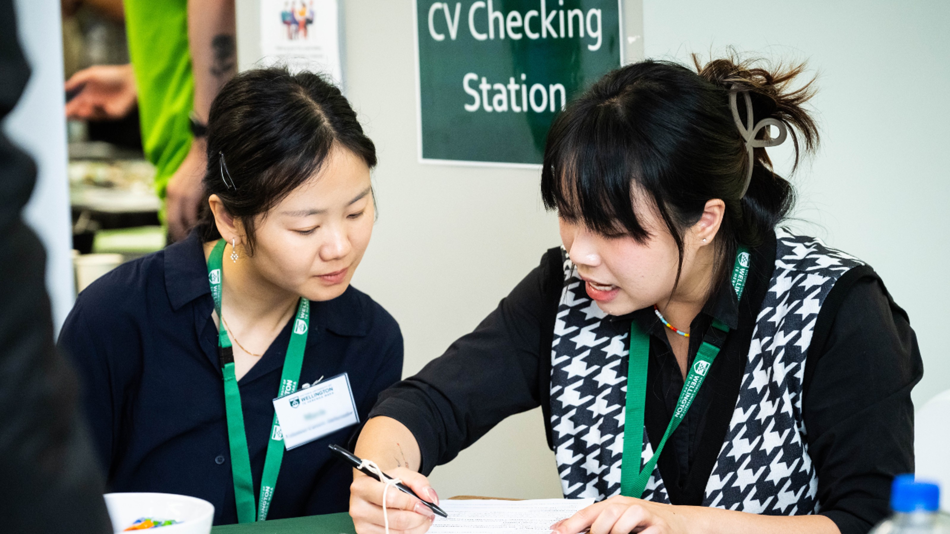 Female careers consultant discussing a CV with an international student at a careers expo CV checking station