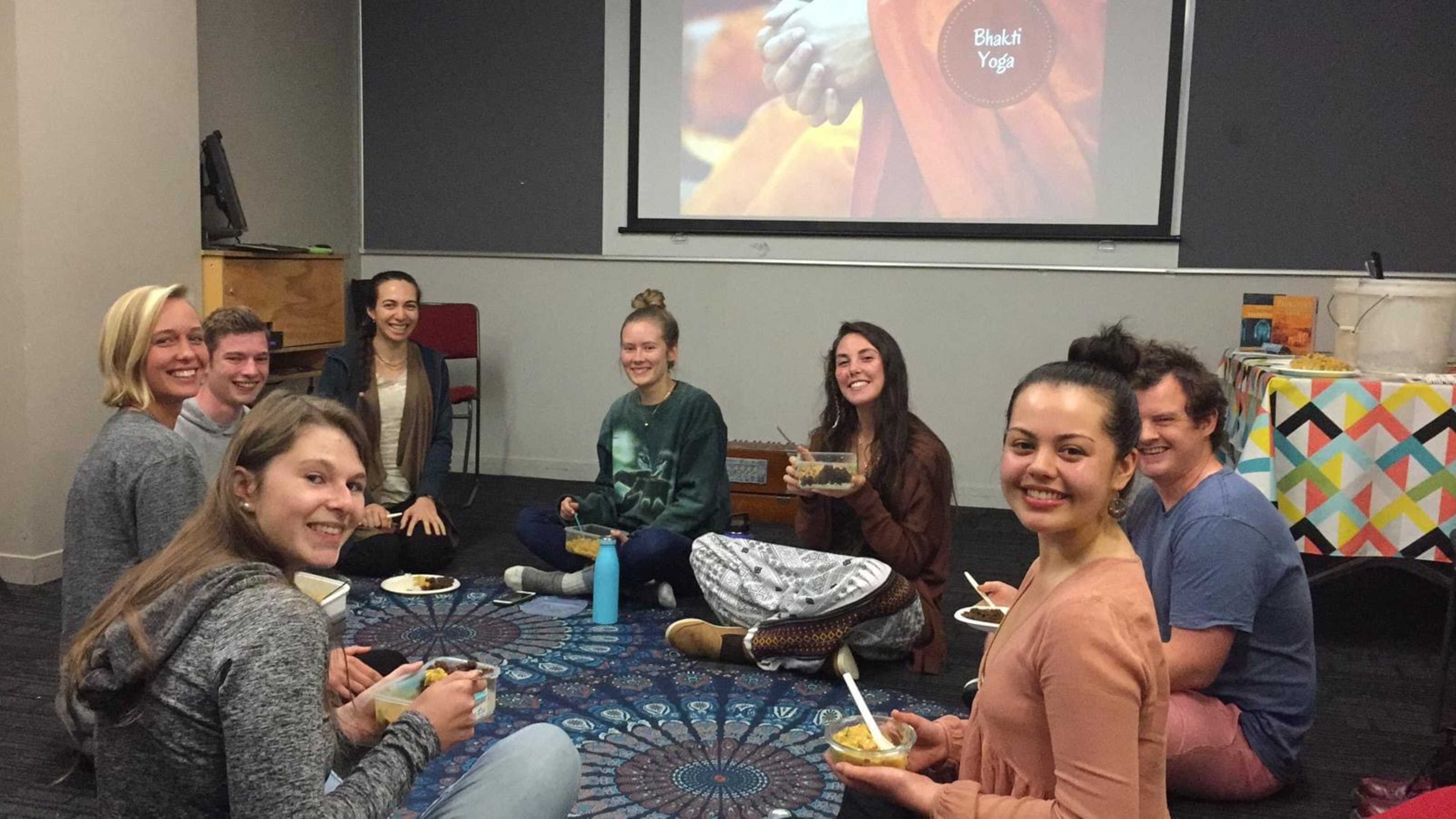 Yoga students sharing curry, sitting on the floor.