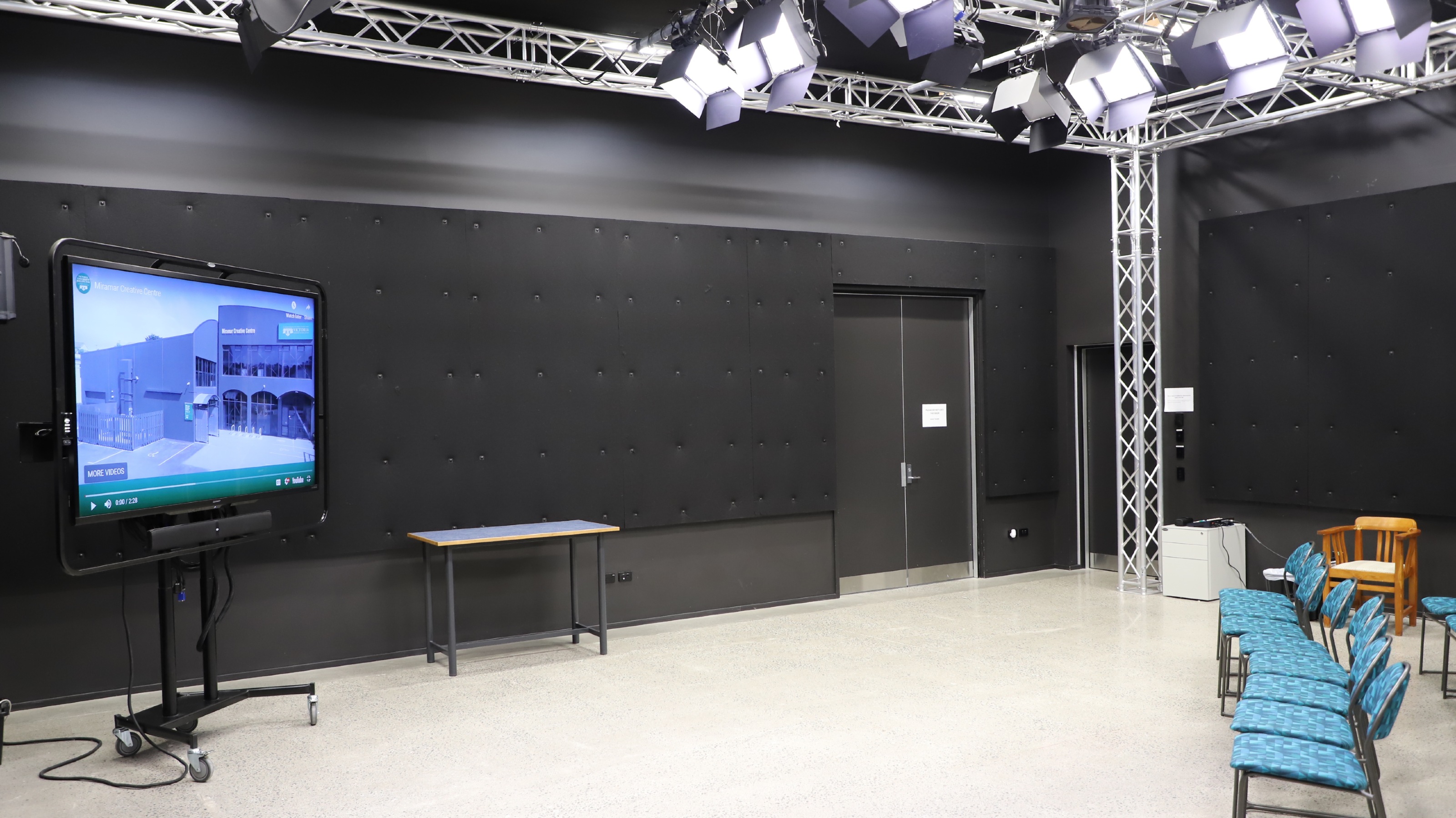 Film studio with TV screen and blue chairs in rows