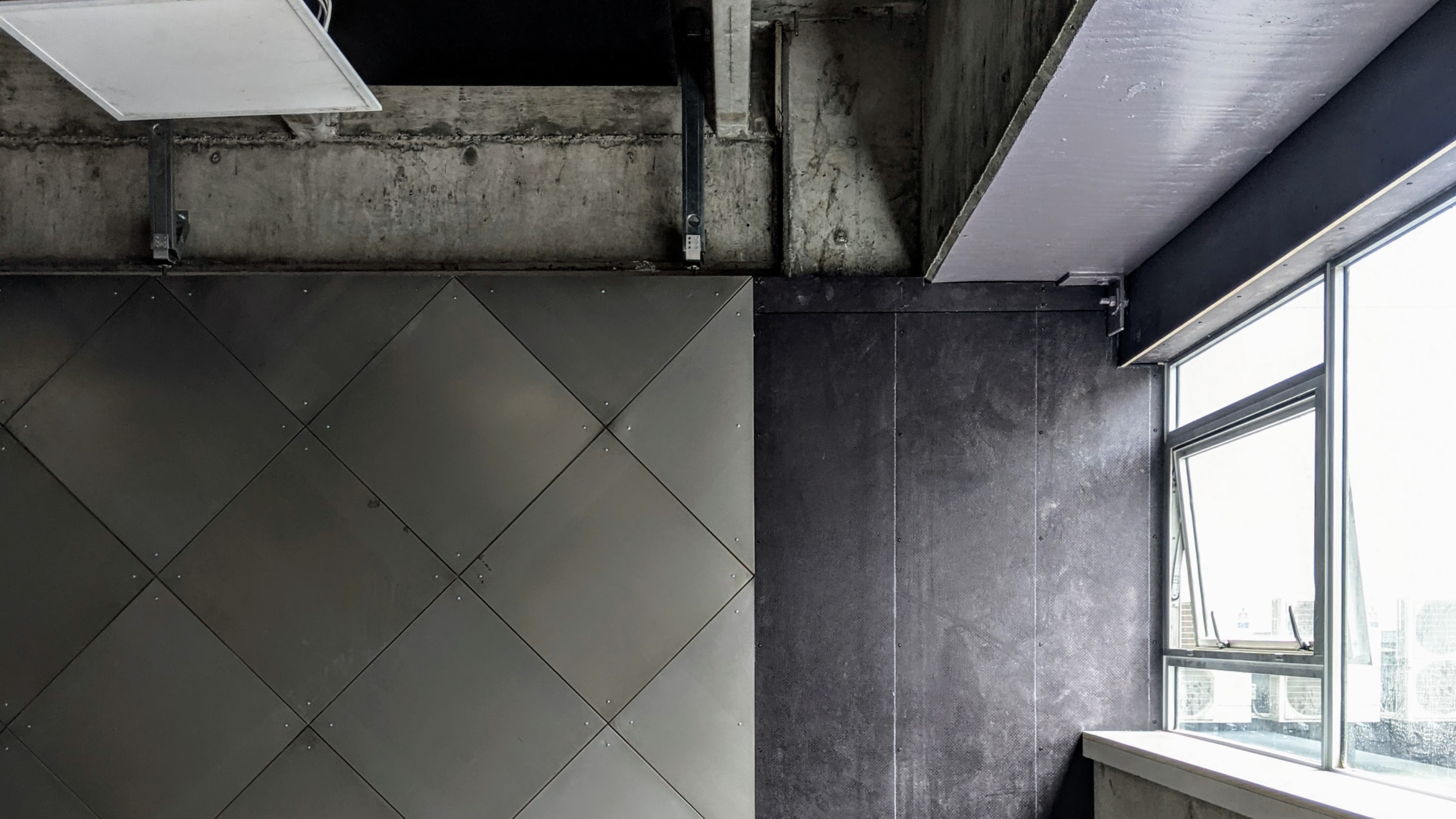 X-frame room divider in an industrial office building clad in black tiles