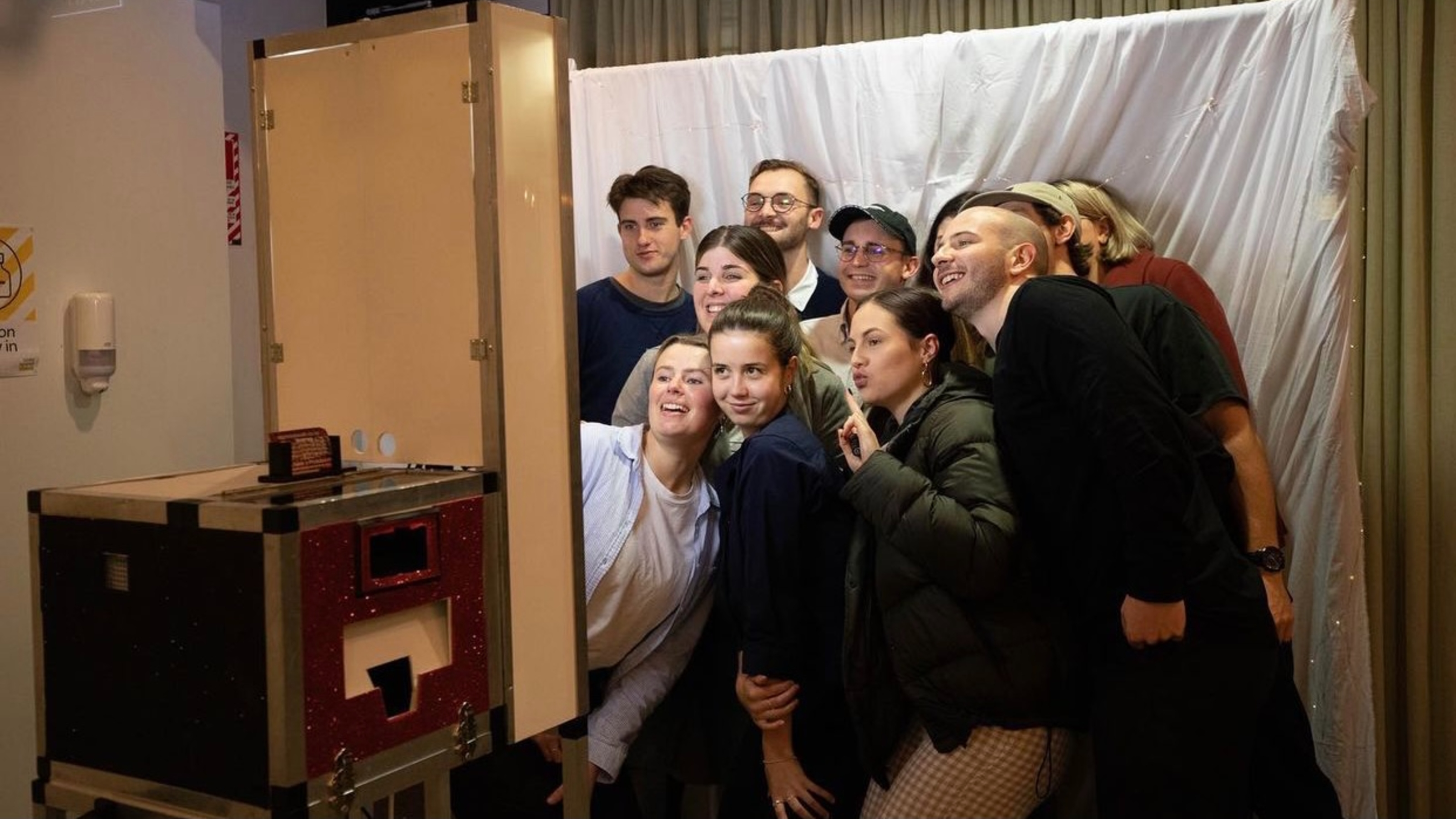 Students trying to all fit for picture in homemade photo booth.