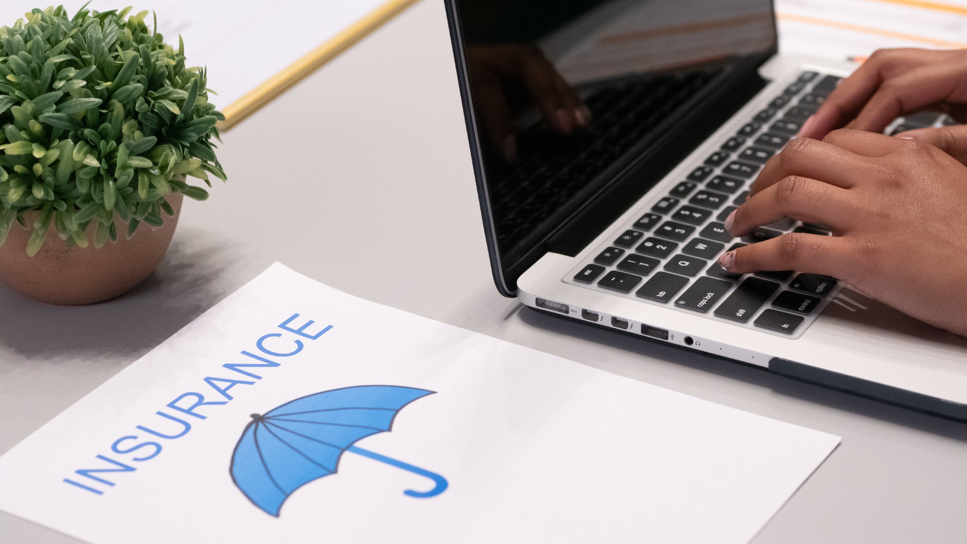 An open laptop next to a piece of paper labelled insurance.