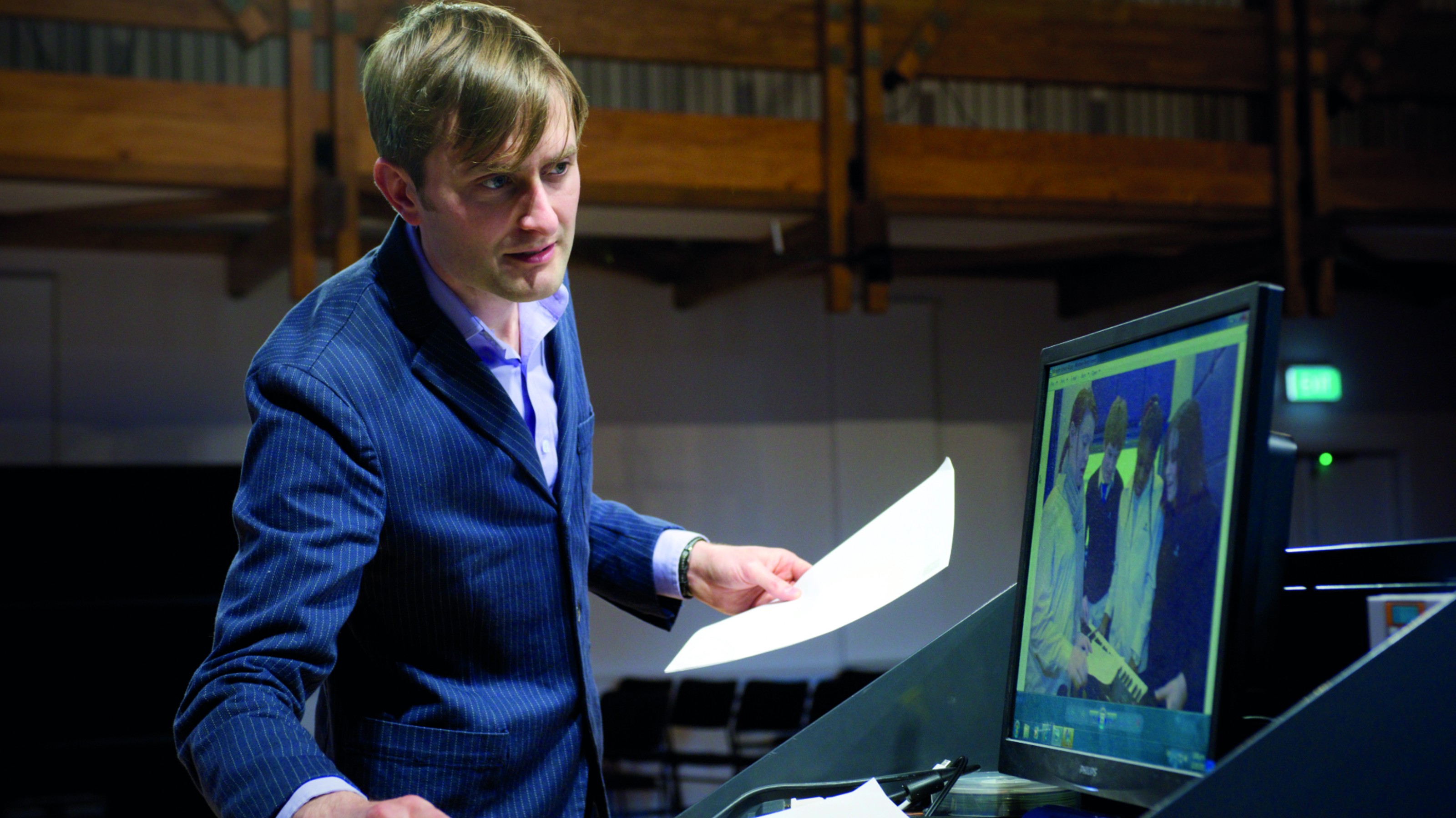 A man standing by a laptop giving a lecture.