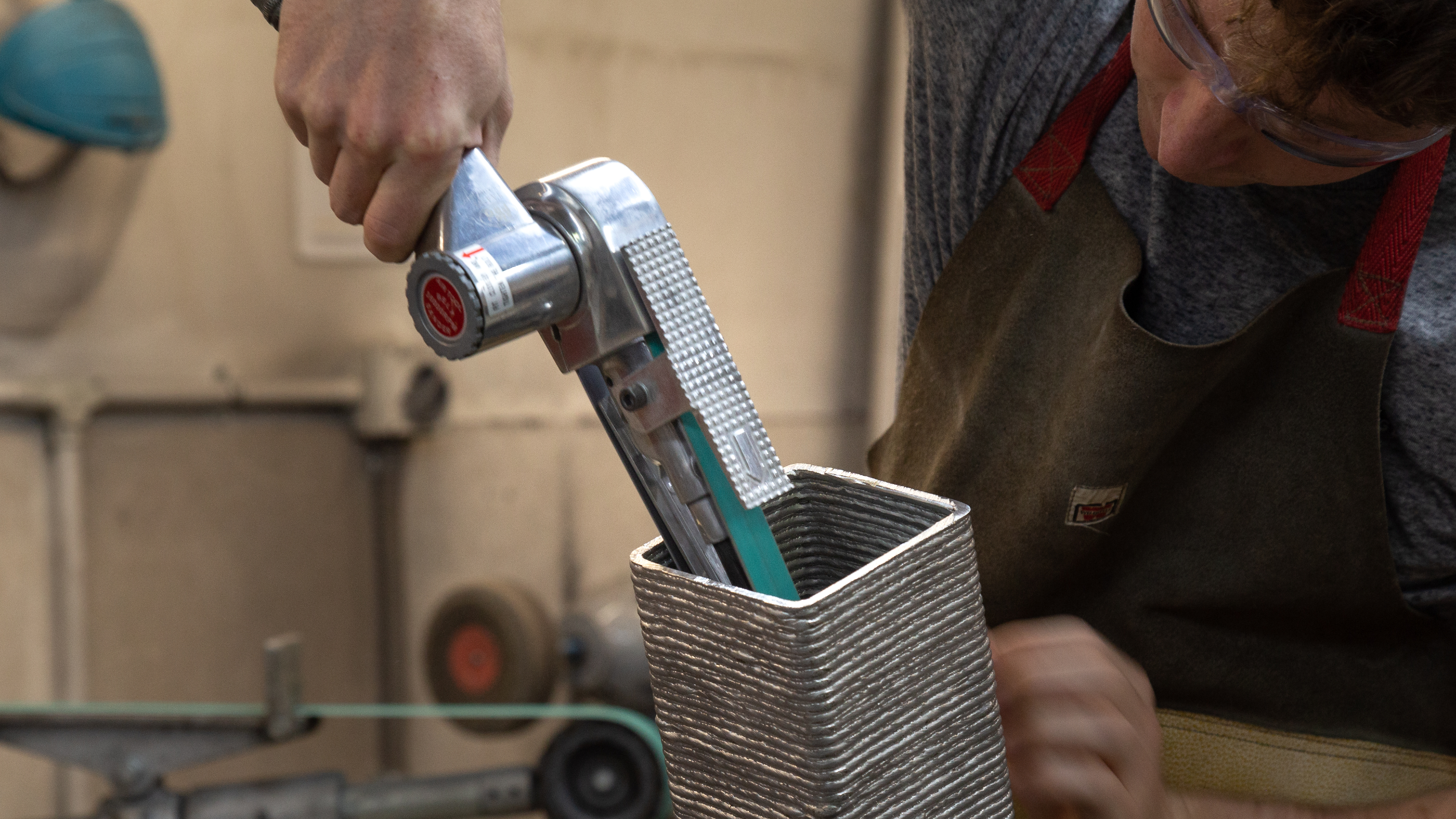 student using hand tool to work on metal model