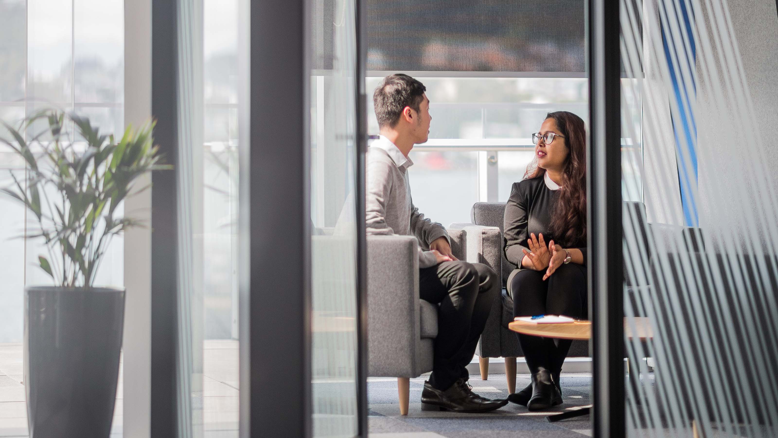 Two students chat in a meeting room in a modern office.
