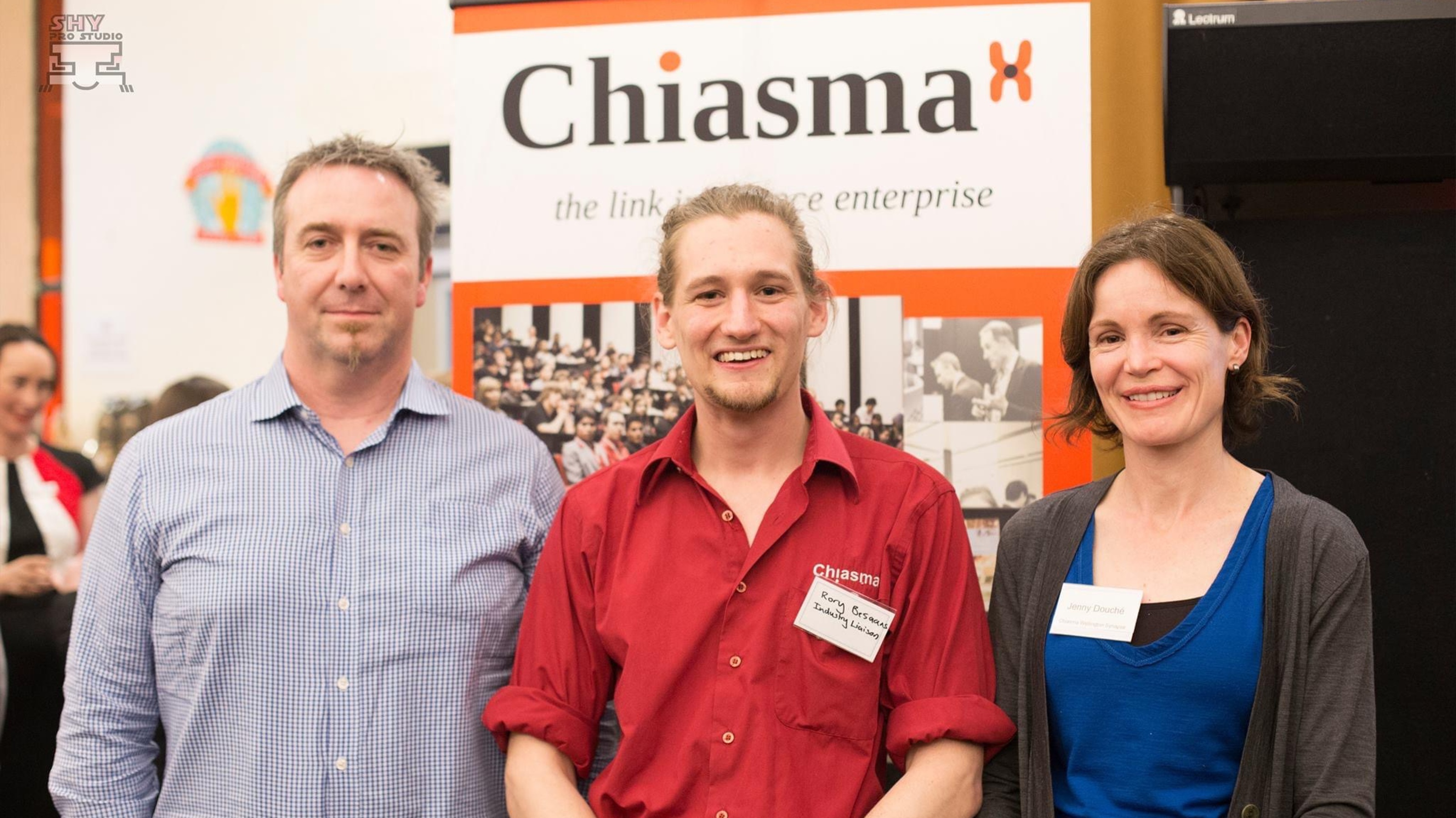 Three Chiasma members standing in front of table at expo.