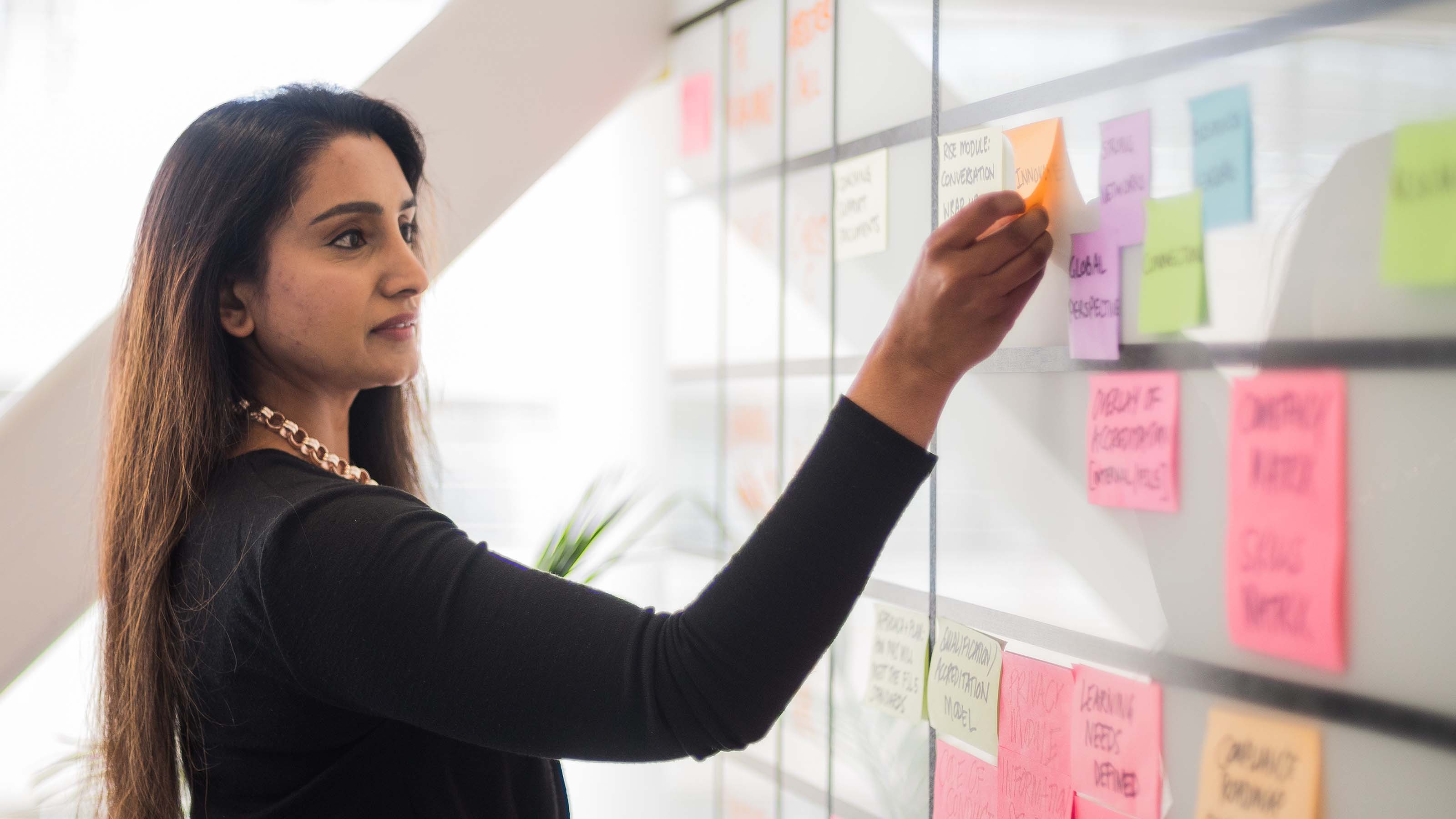 A female student moves a post-it note on a kanban board.