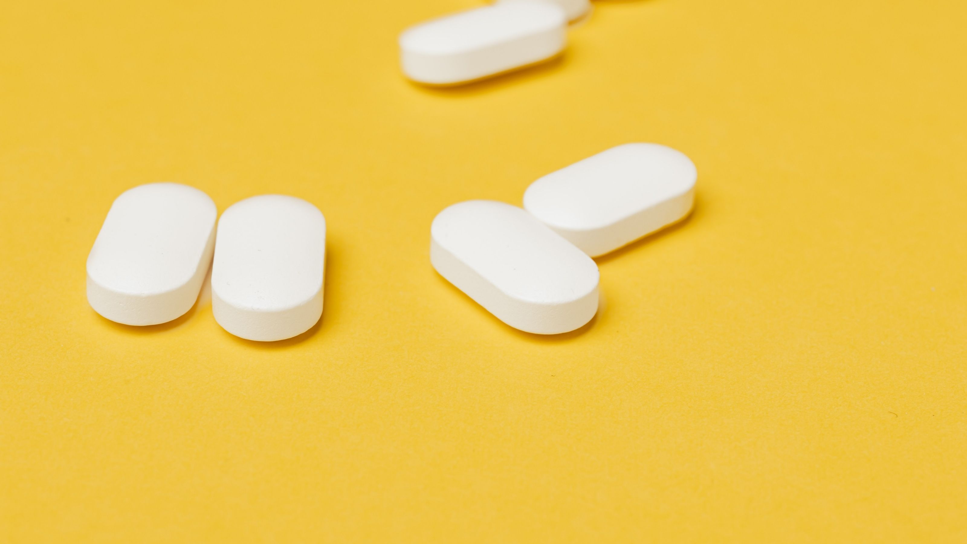 Group of white pills on yellow background