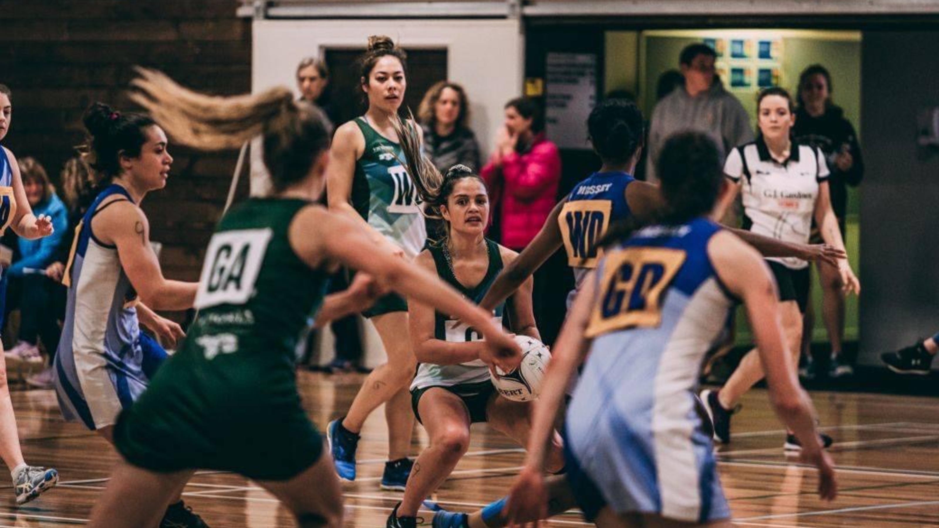 Netball player holding ball while other players run.