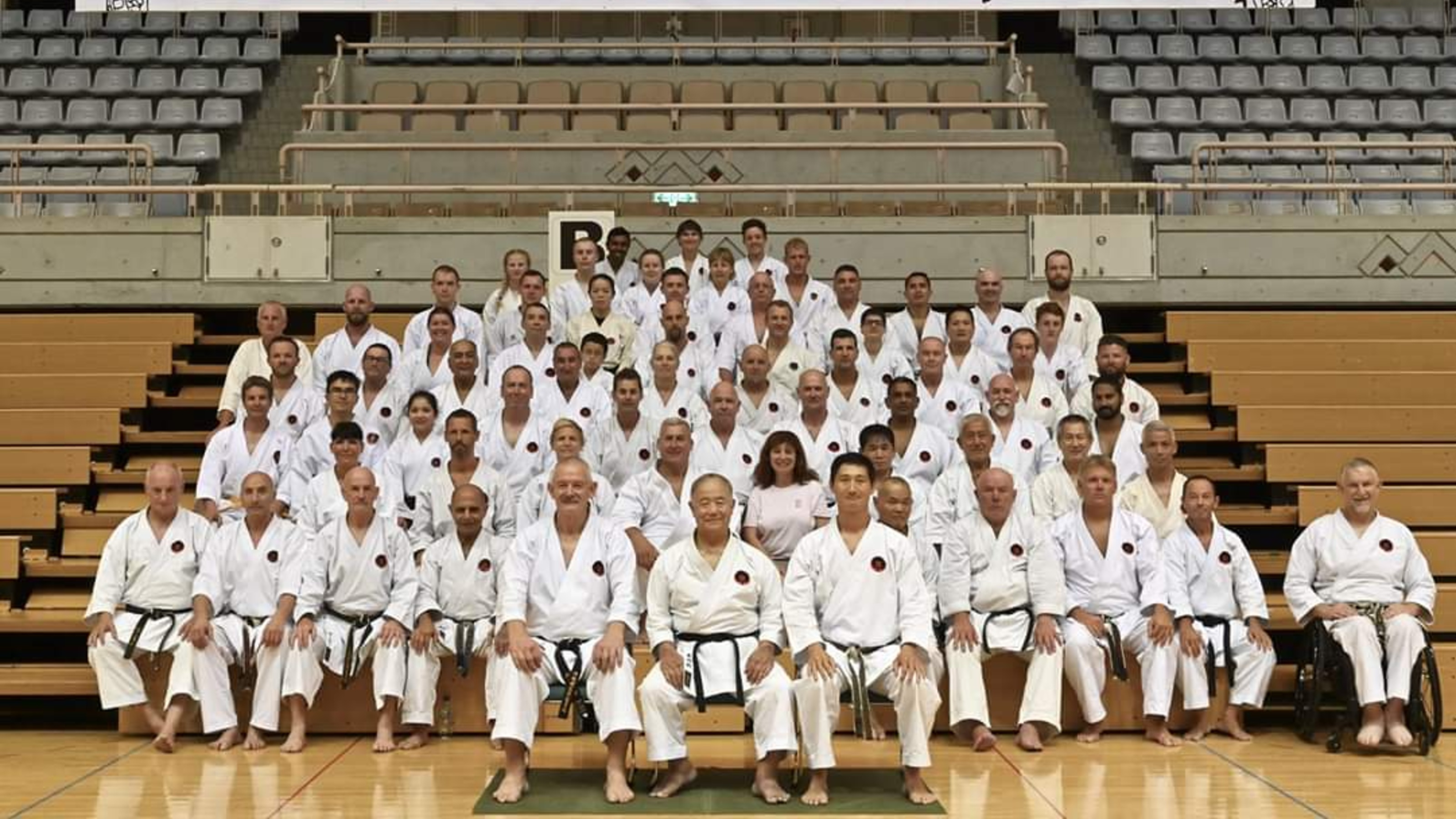 Group picture of karate trainees, all sitting upright with hands on their knees.