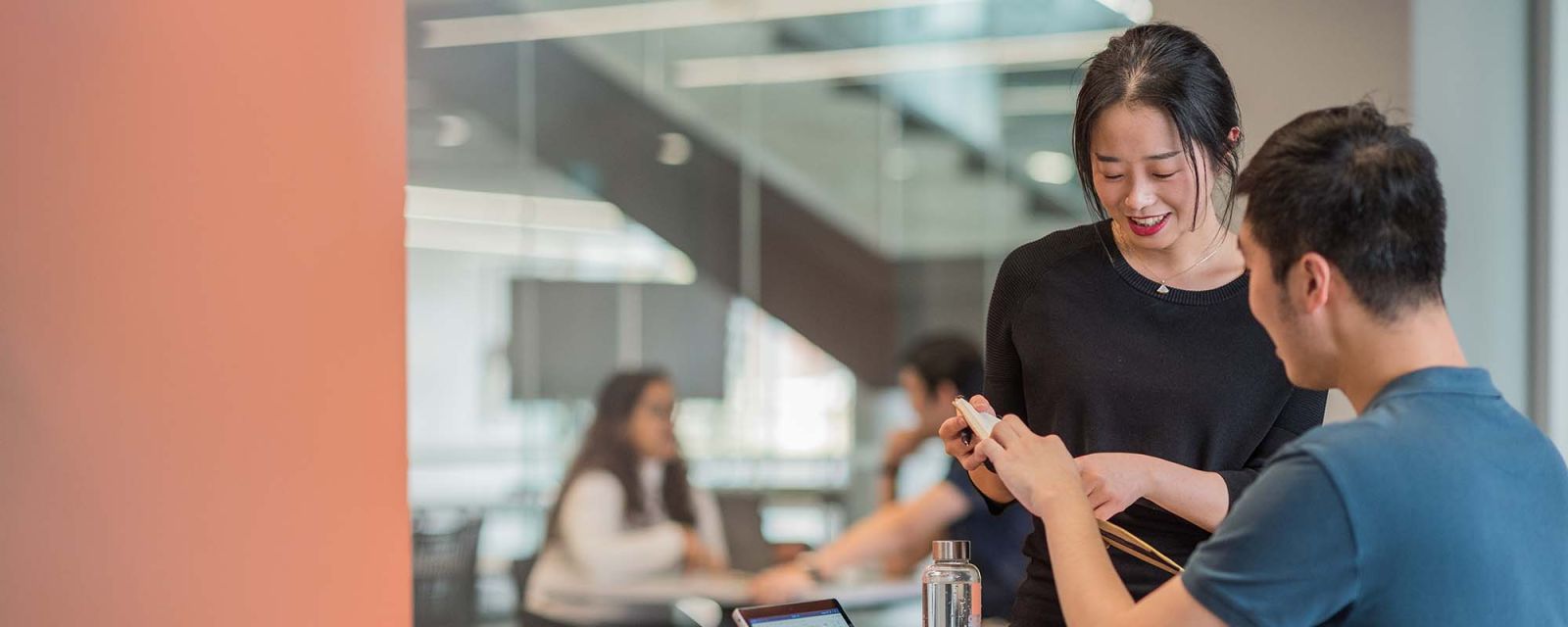 Two people talk to each other at a table in a study area