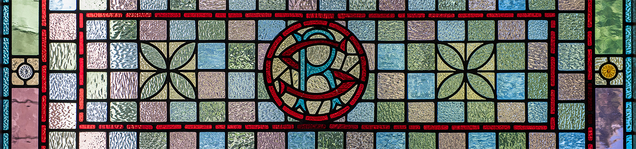 An image of a stained glass window with the letters R and S encircled in the middle.