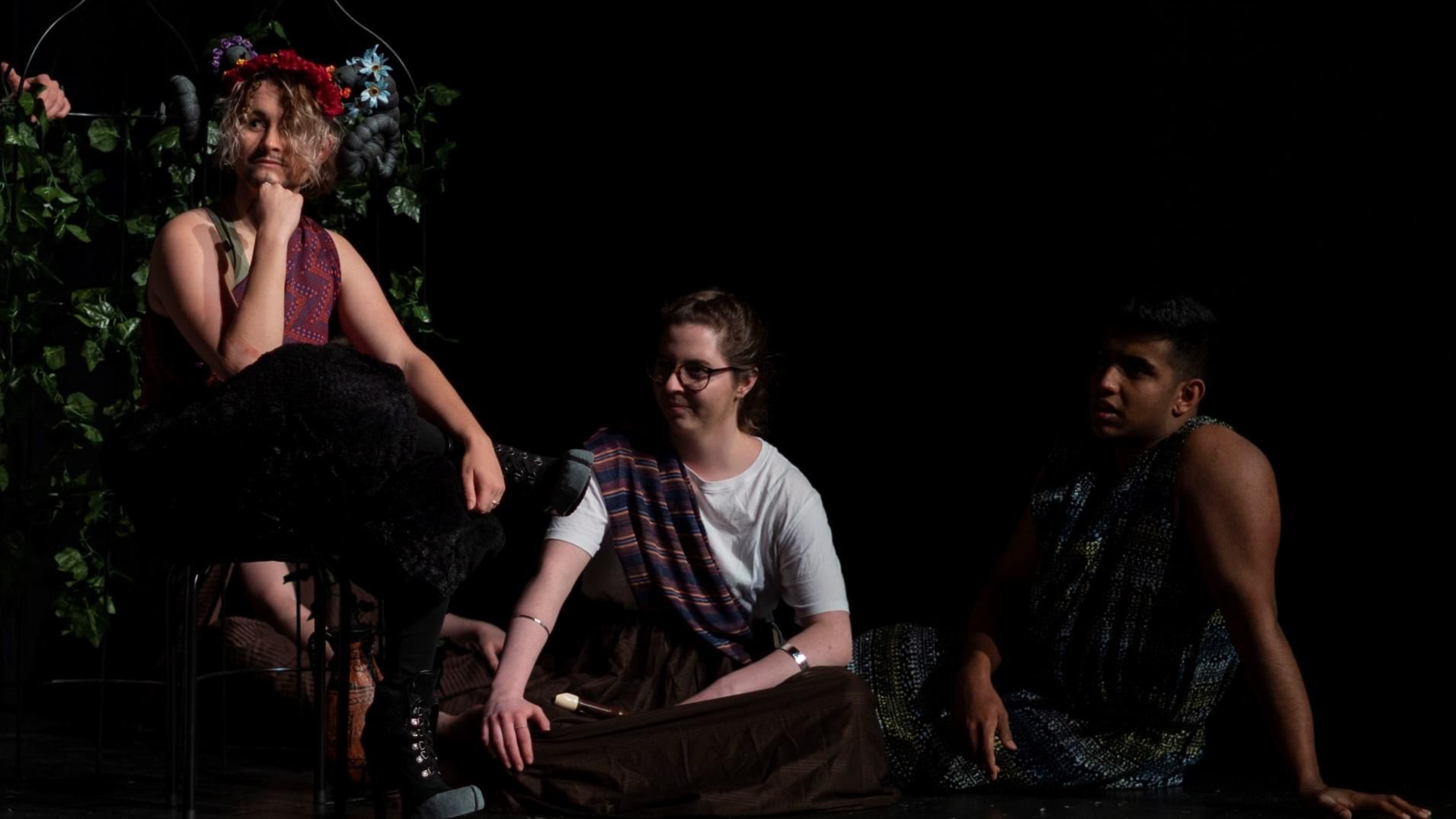 Performance with faun sitting in bush and two other figures sitting on the floor.