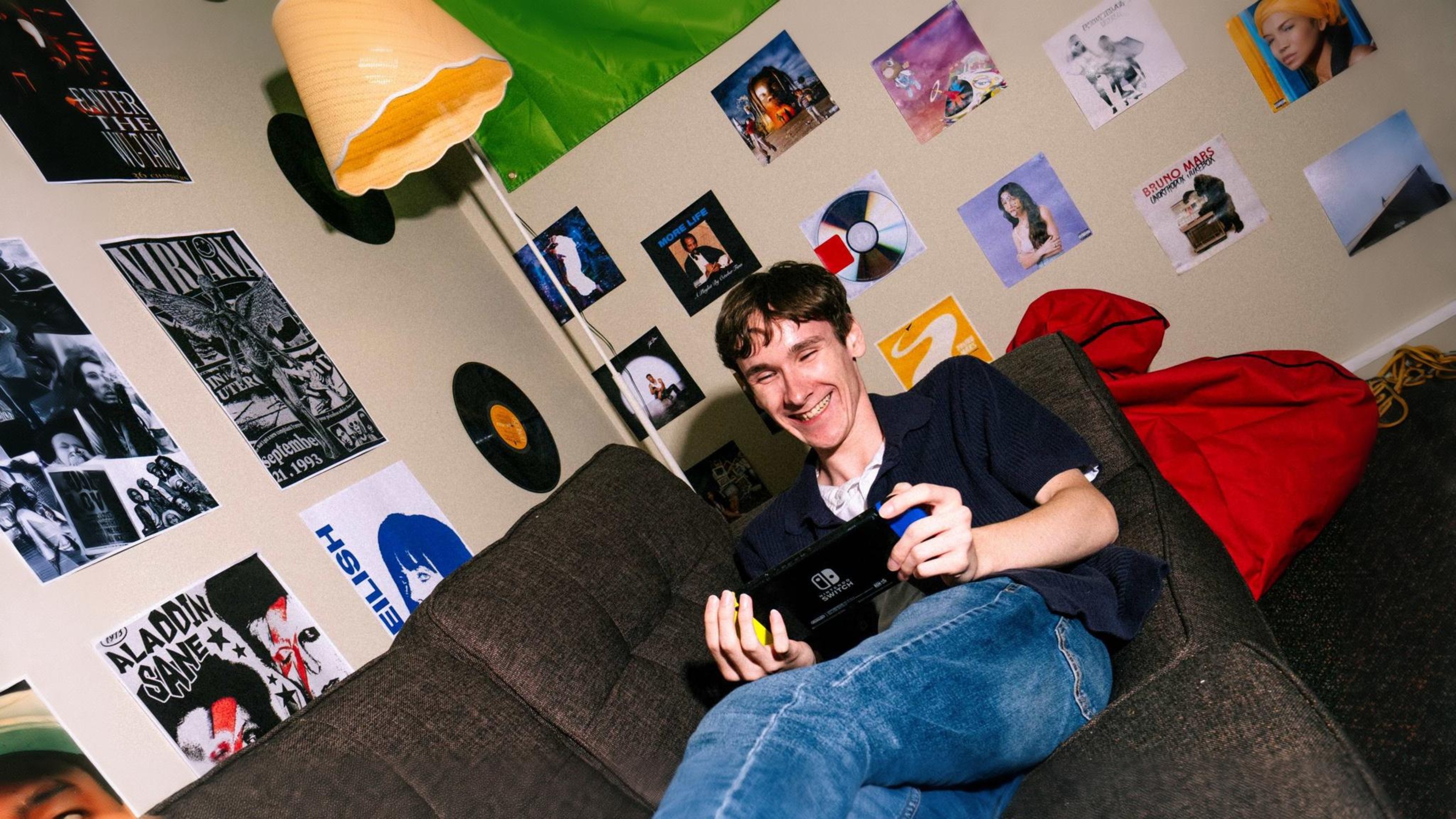 Man playing hand held computer game on couch.