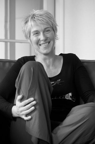 A black and white image of Paula Boock sitting on a sofa.