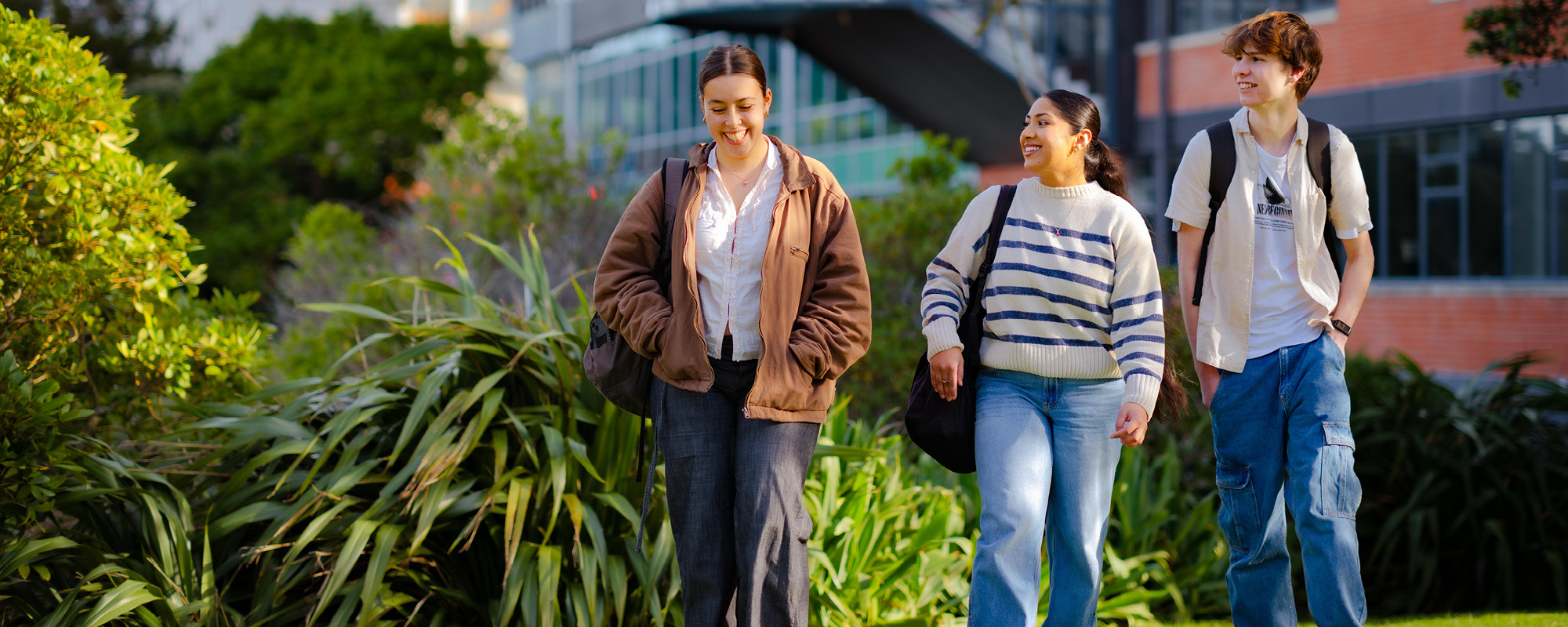 Three students are walking outdoors on campus
