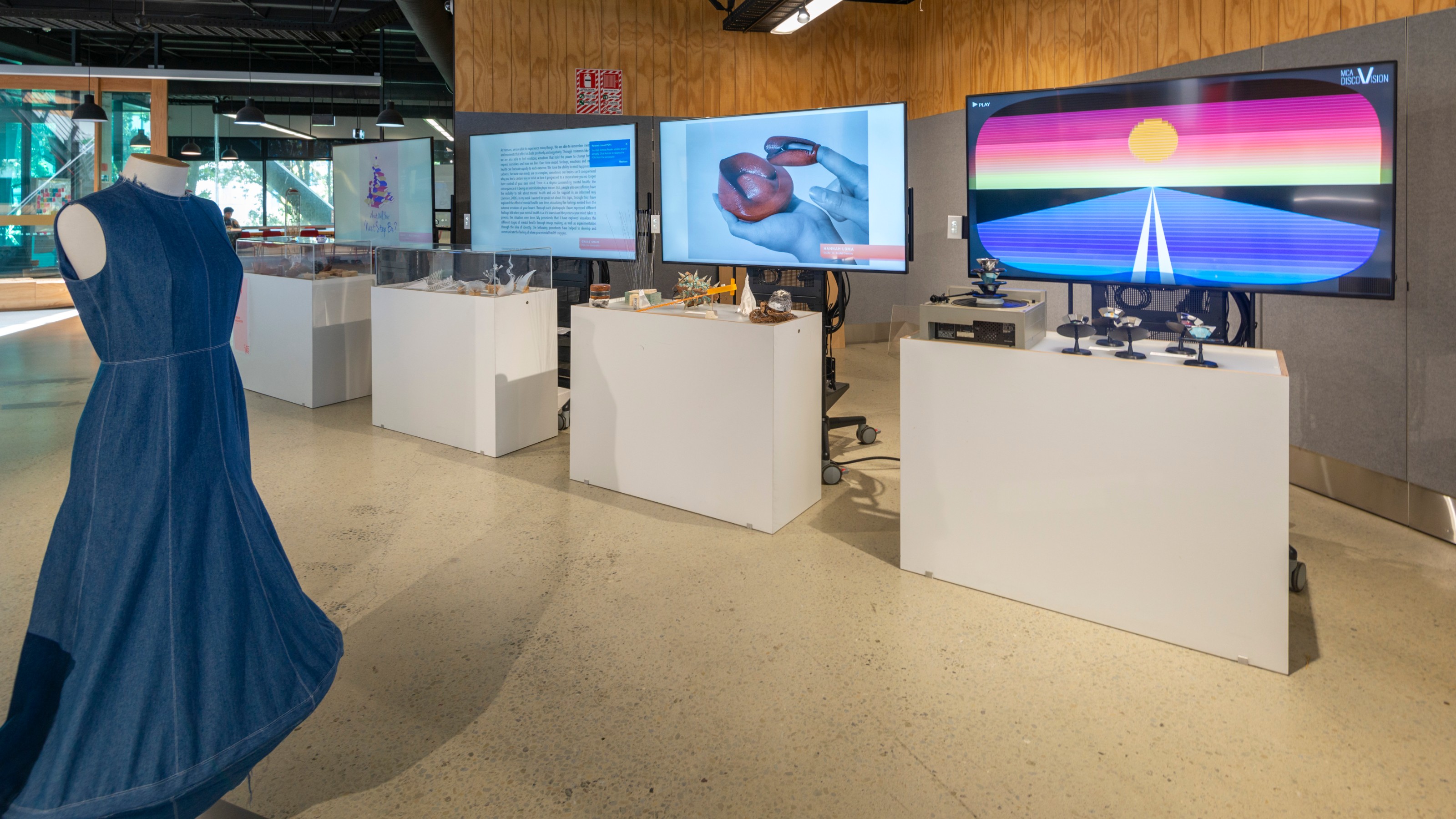 Blue dress in front of displays of Design students work at Wellington Faculty of Architecture and Design Innovation End of Year Exhibition 2019