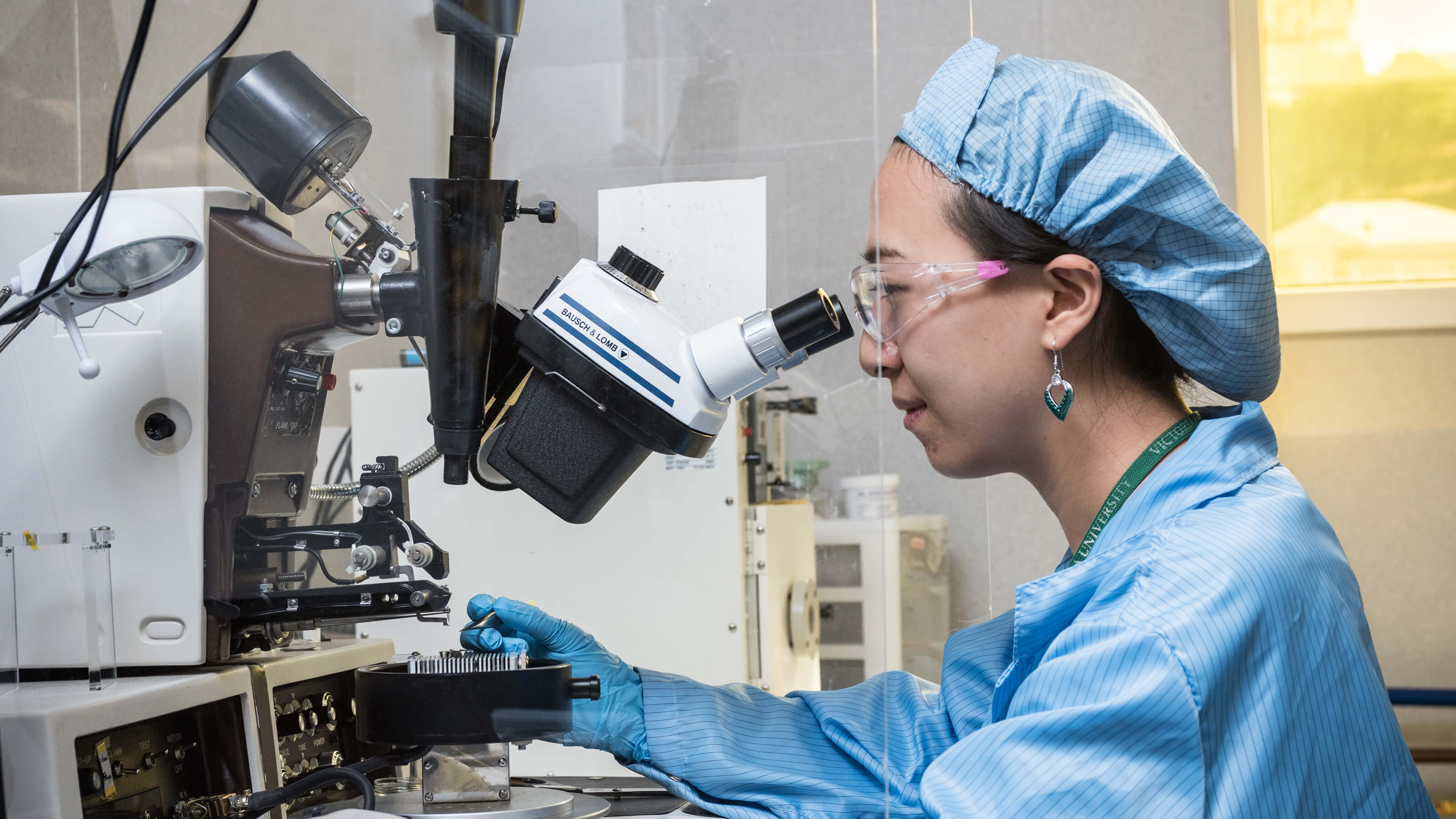 Science research student in a lab looking into microscope.