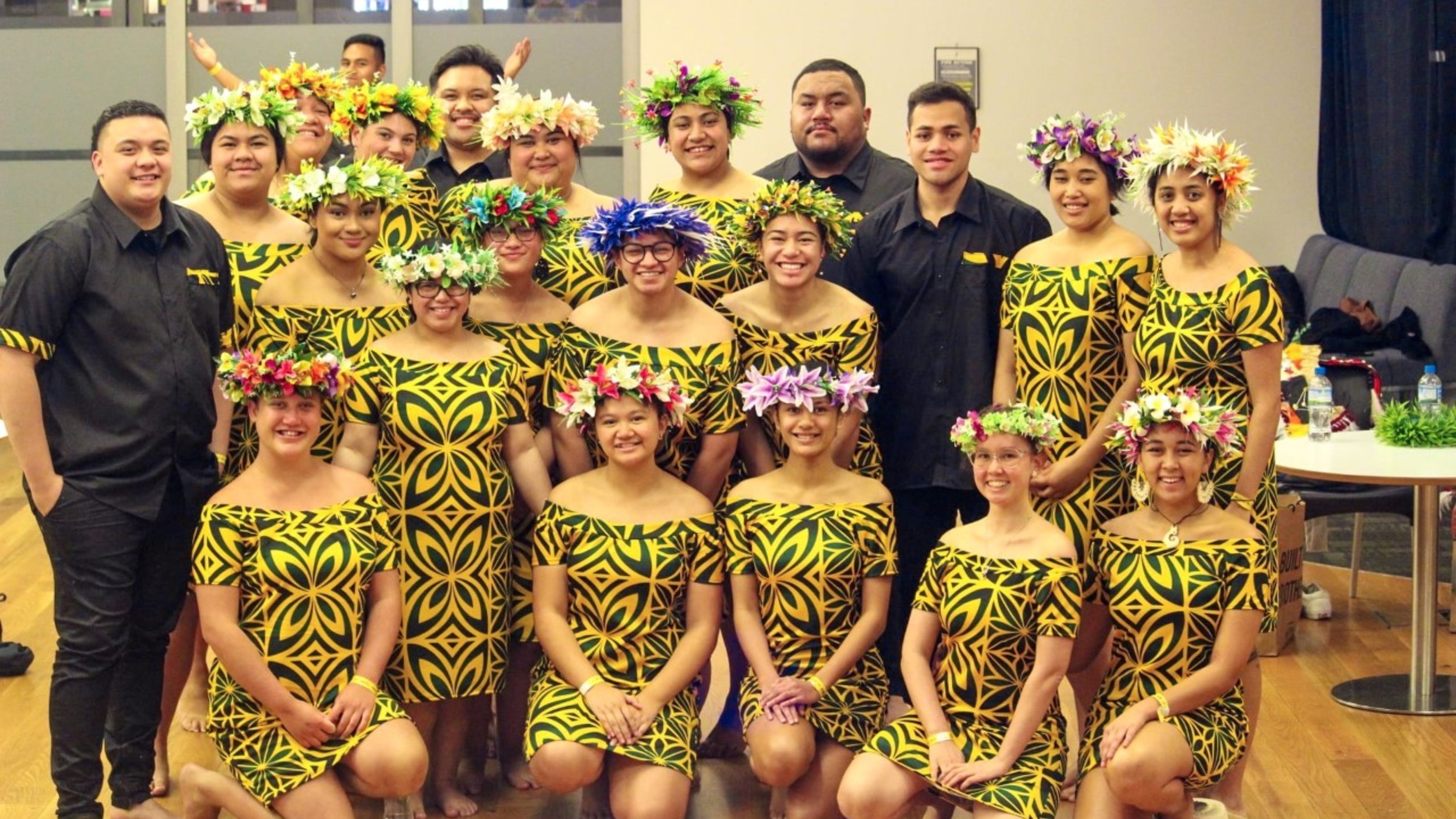 Group picture of students wearing black and yellow dresses and flower crowns.
