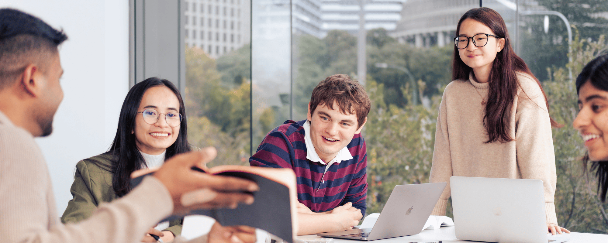 Five students working together around a table with laptops in a study space at Victoria University of Wellington's Pipitea campus.