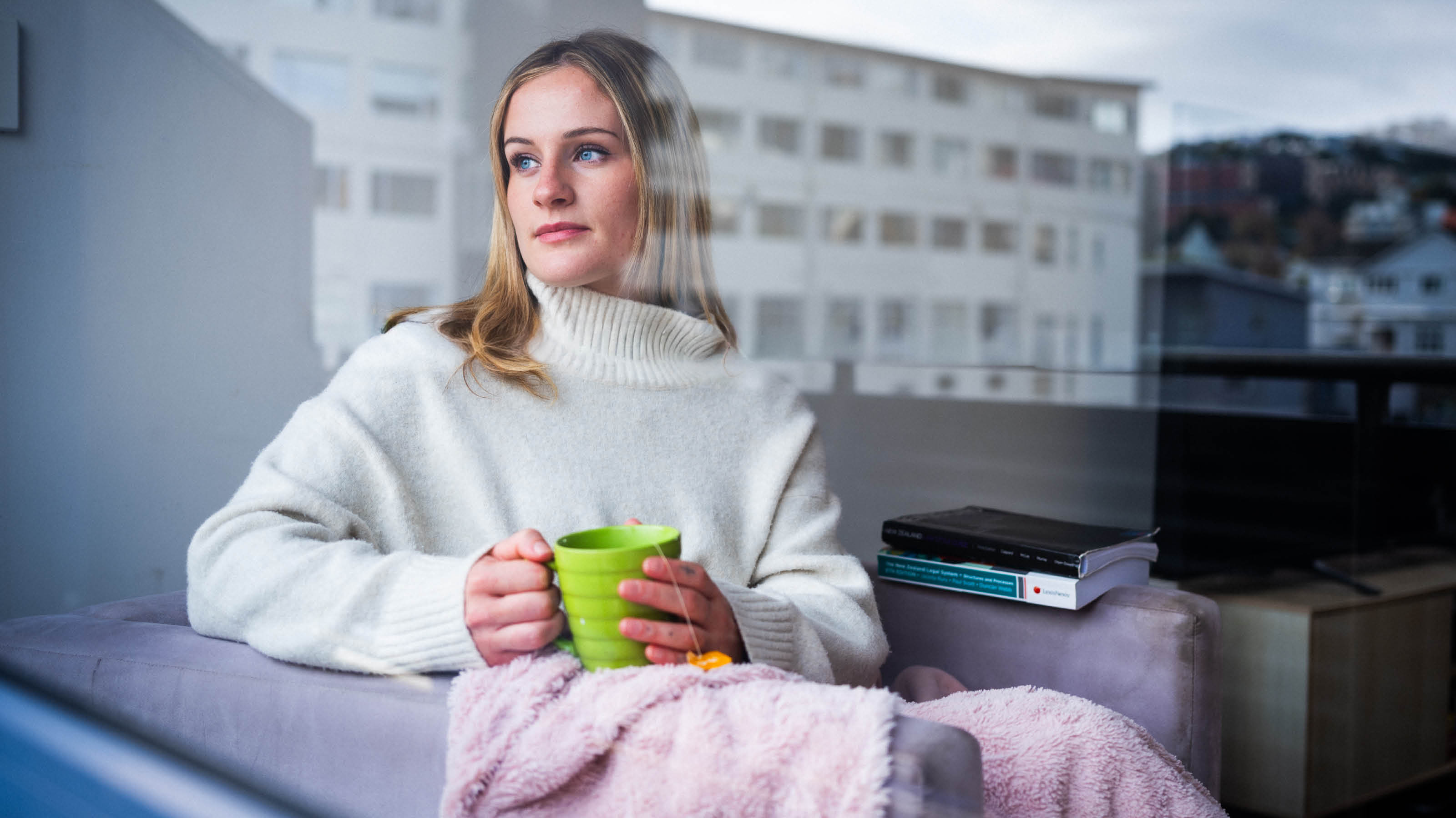 A student holds a ceramic mug of tea while standing in her flat's lounge