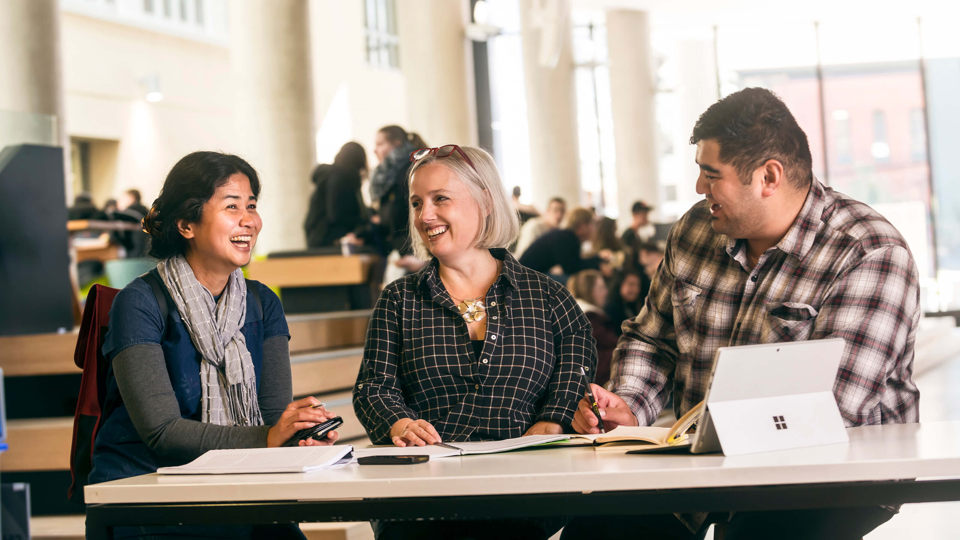 Three people sit at a table and have a friendly discussion.