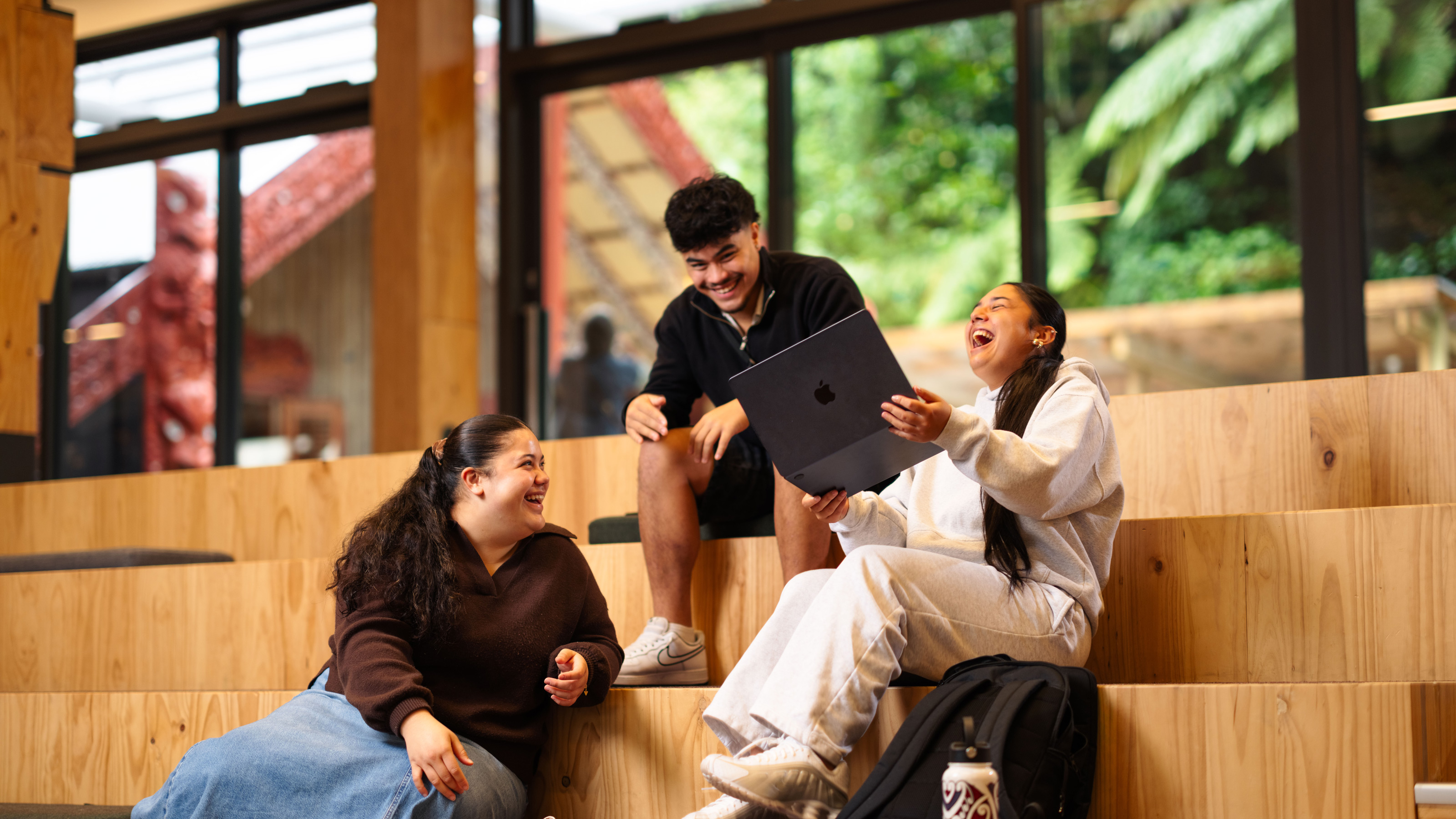 Three students sitting on stairs and laughing together