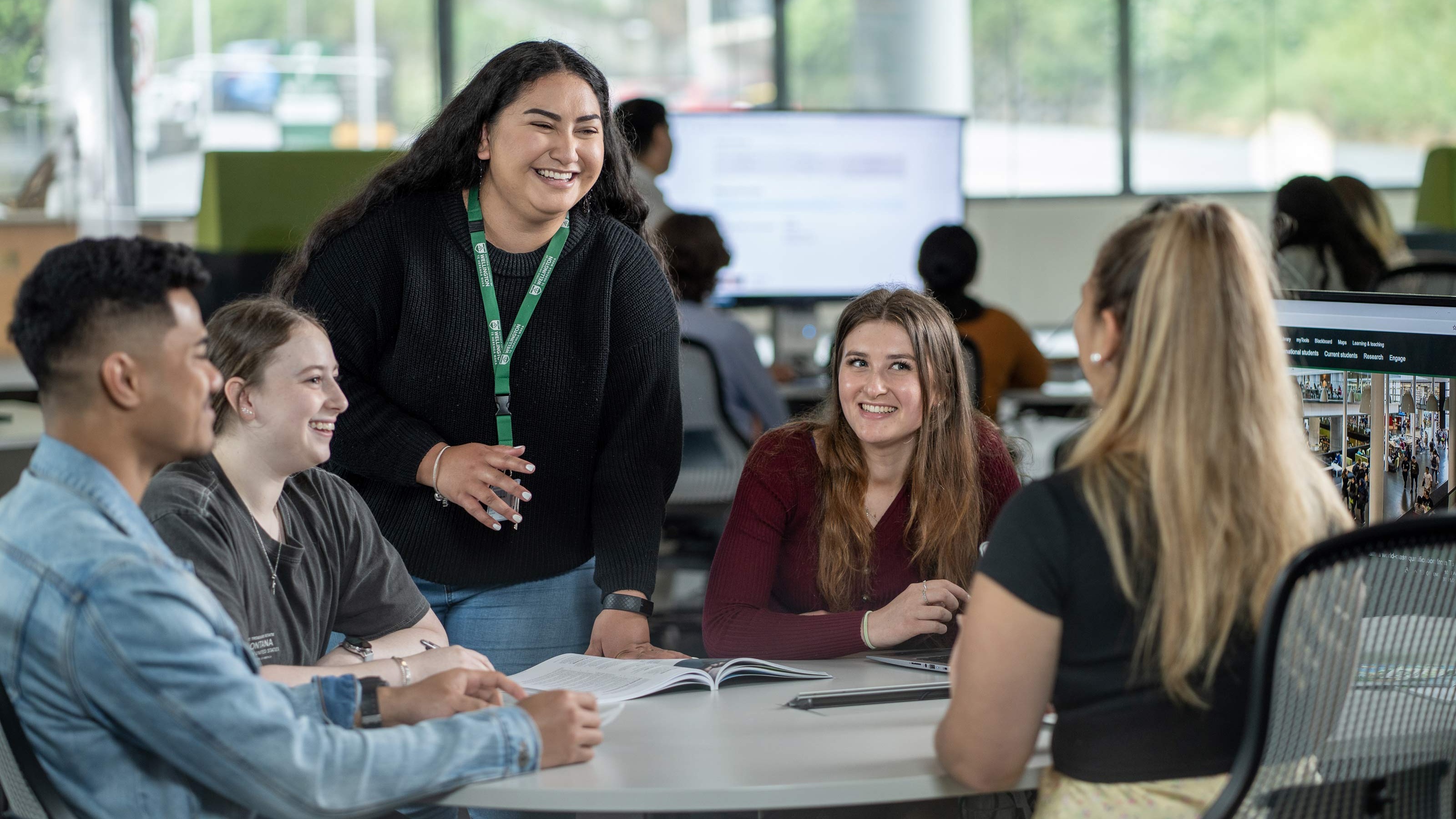 A Future Student Adviser chats to a group of four prospective students around a table at a course planning event.