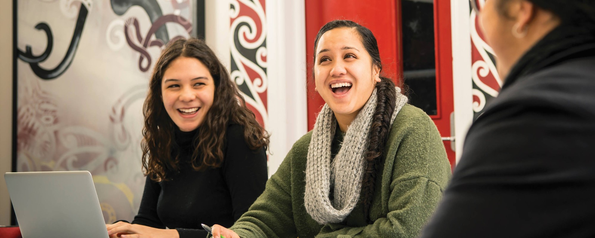 Three women laughing in a casual study interaction