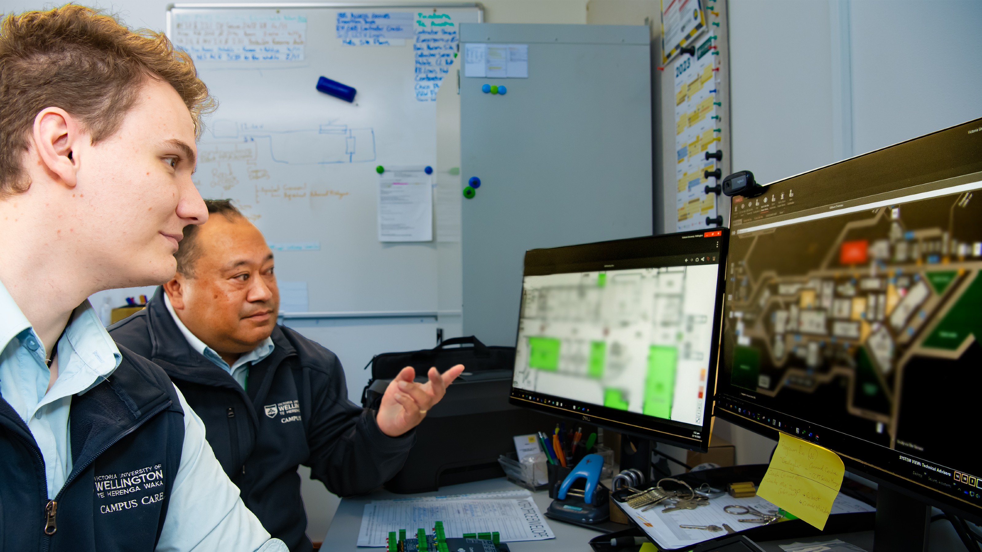 Two Campus Secuirty staff at a desk looking at computer screens