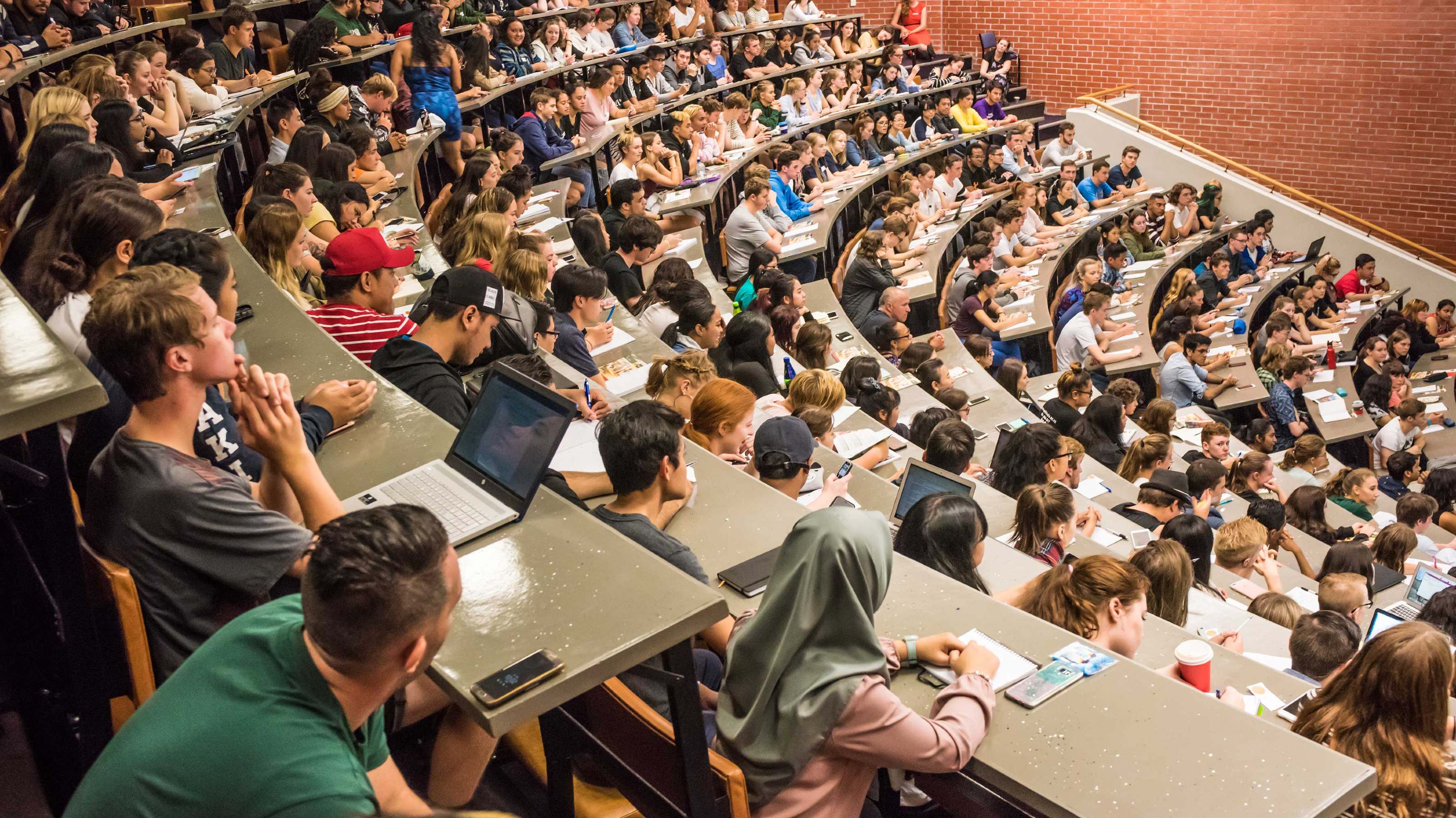 View looking down from top of large lecture theatre full of students.