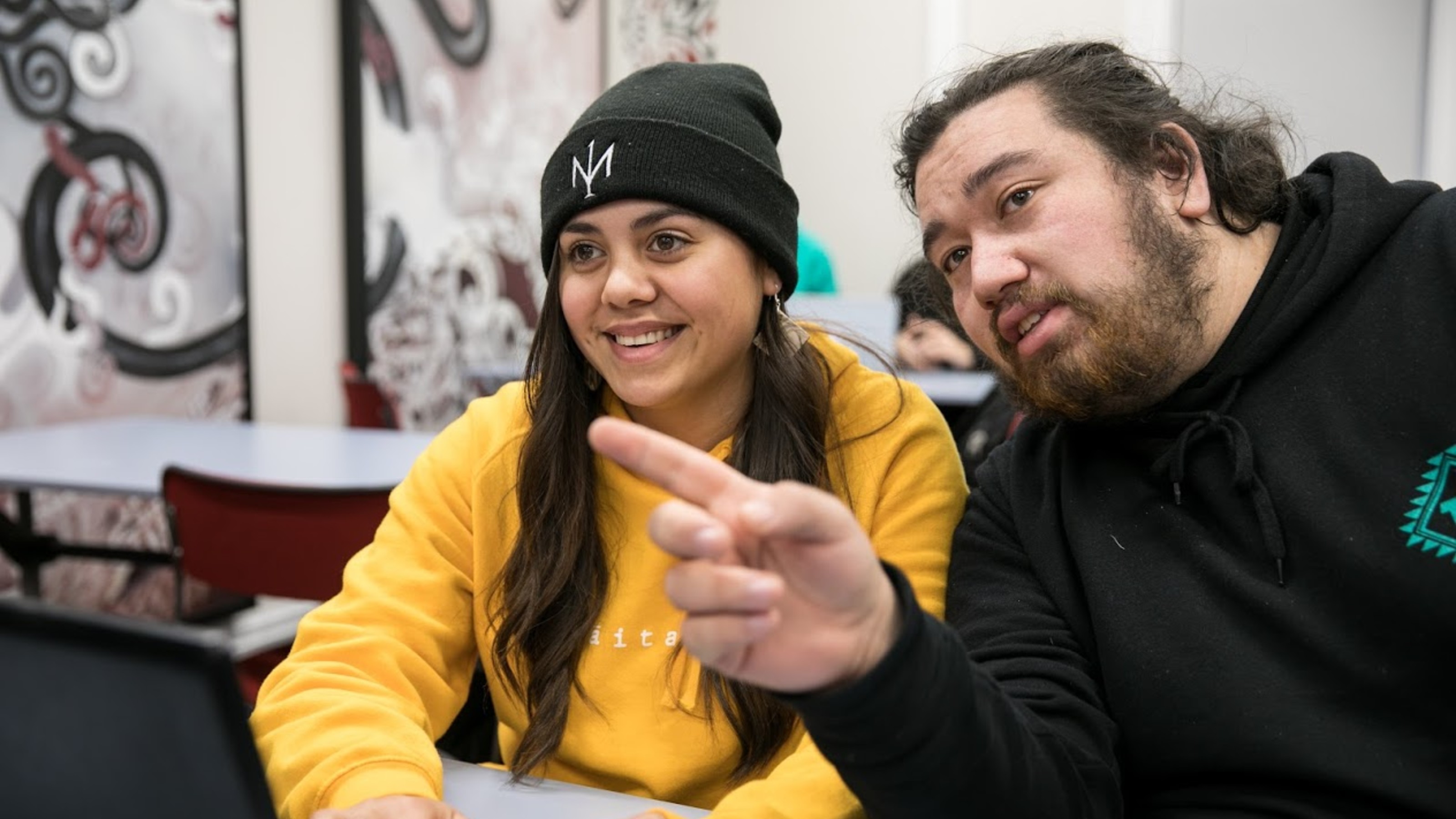 Two students sitting in front of a laptop.