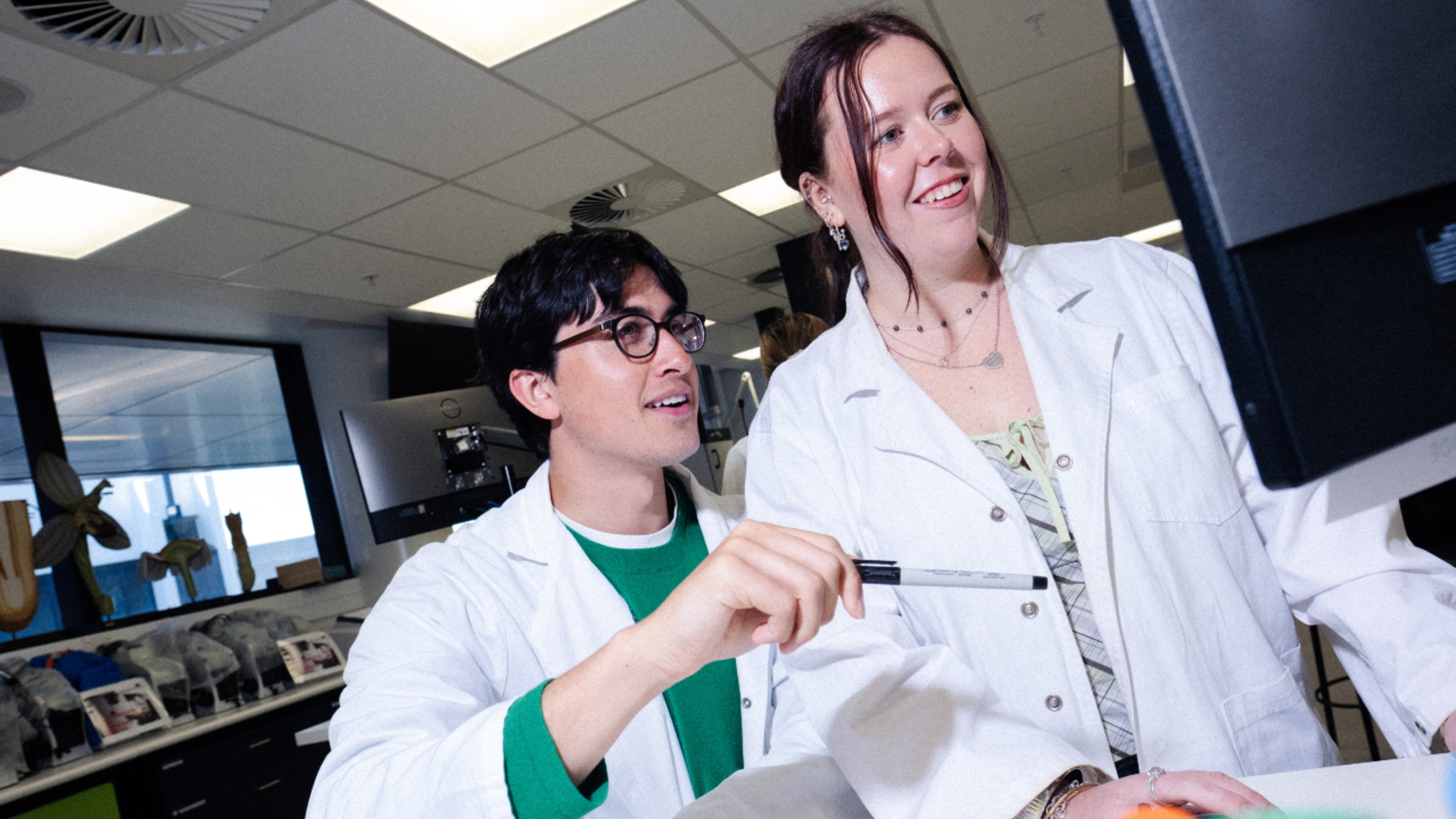 Two students in a lab looking at something on a monitor