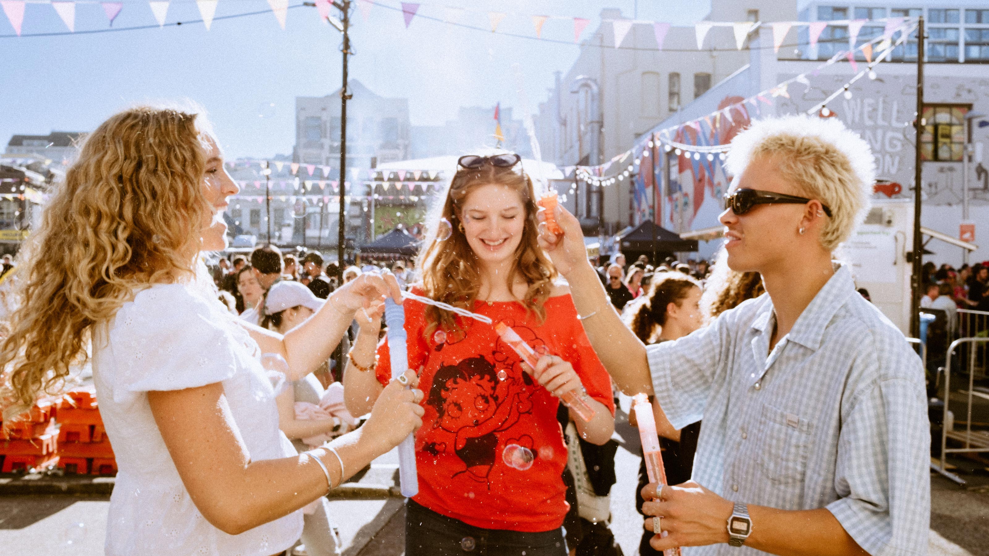 Three students on a busy street using bubble wands