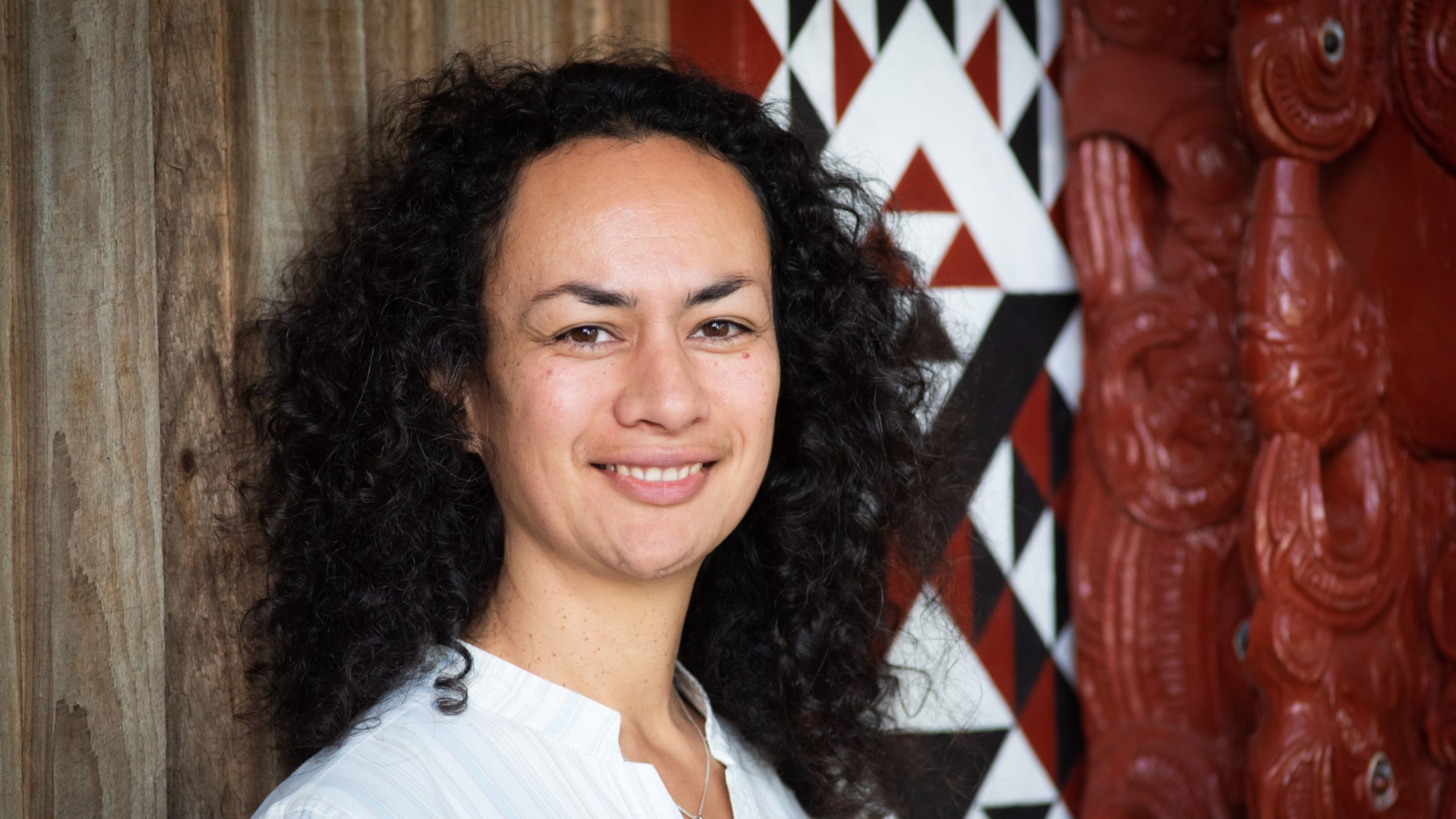 Professor Ocean Mercier stands in front of marae carvings.