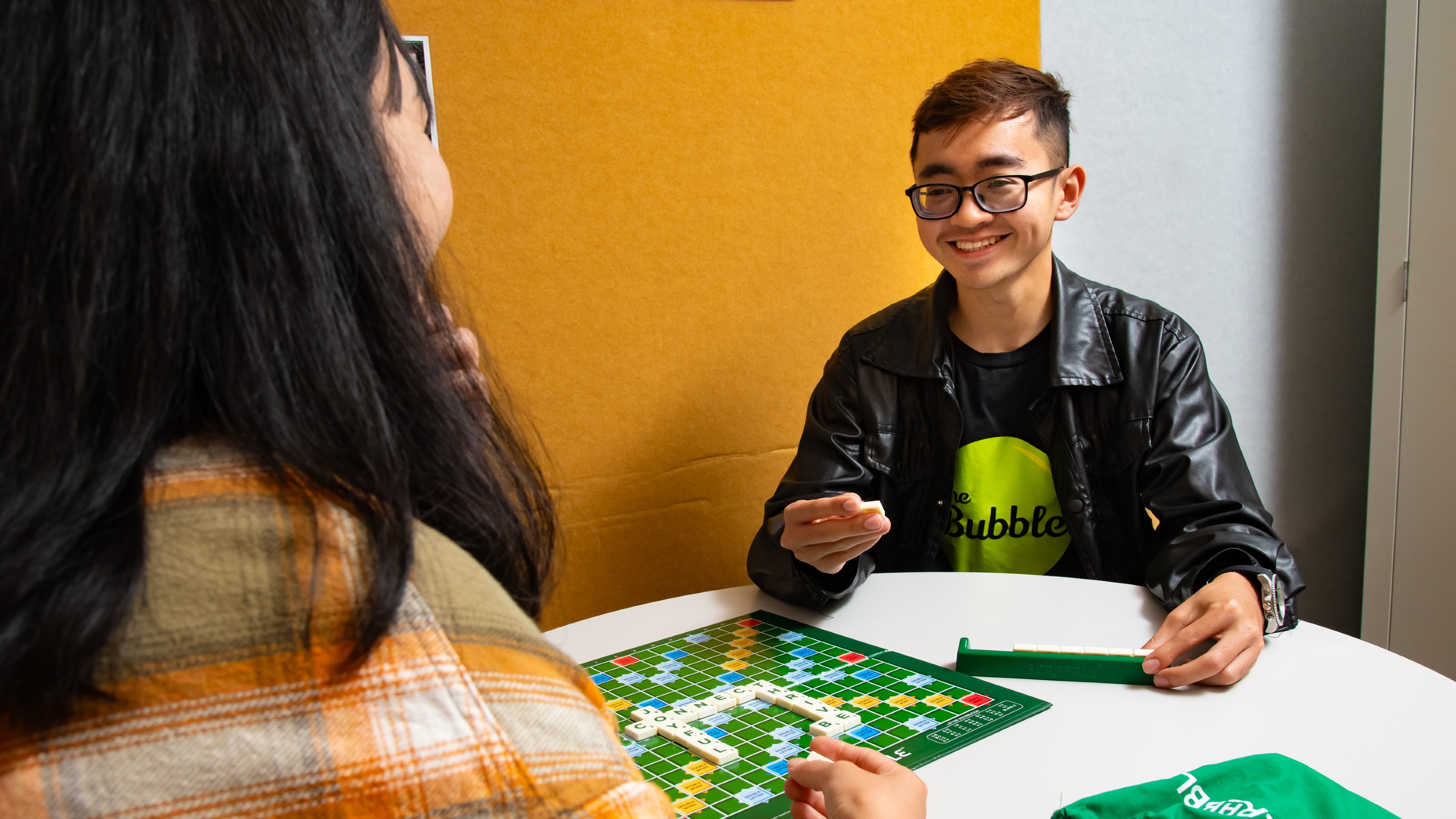 Two students playing scrabble at a table in The Bubble.