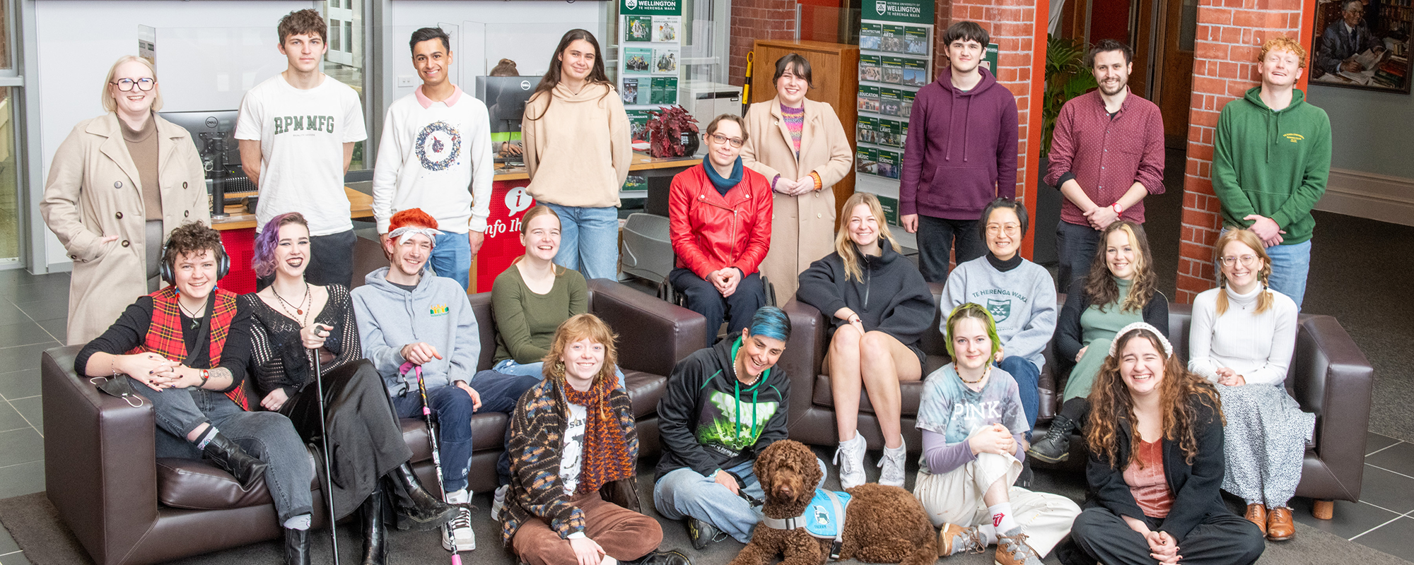 Twenty-one diverse disabled students posing for a photo in the Hunter building atrium.