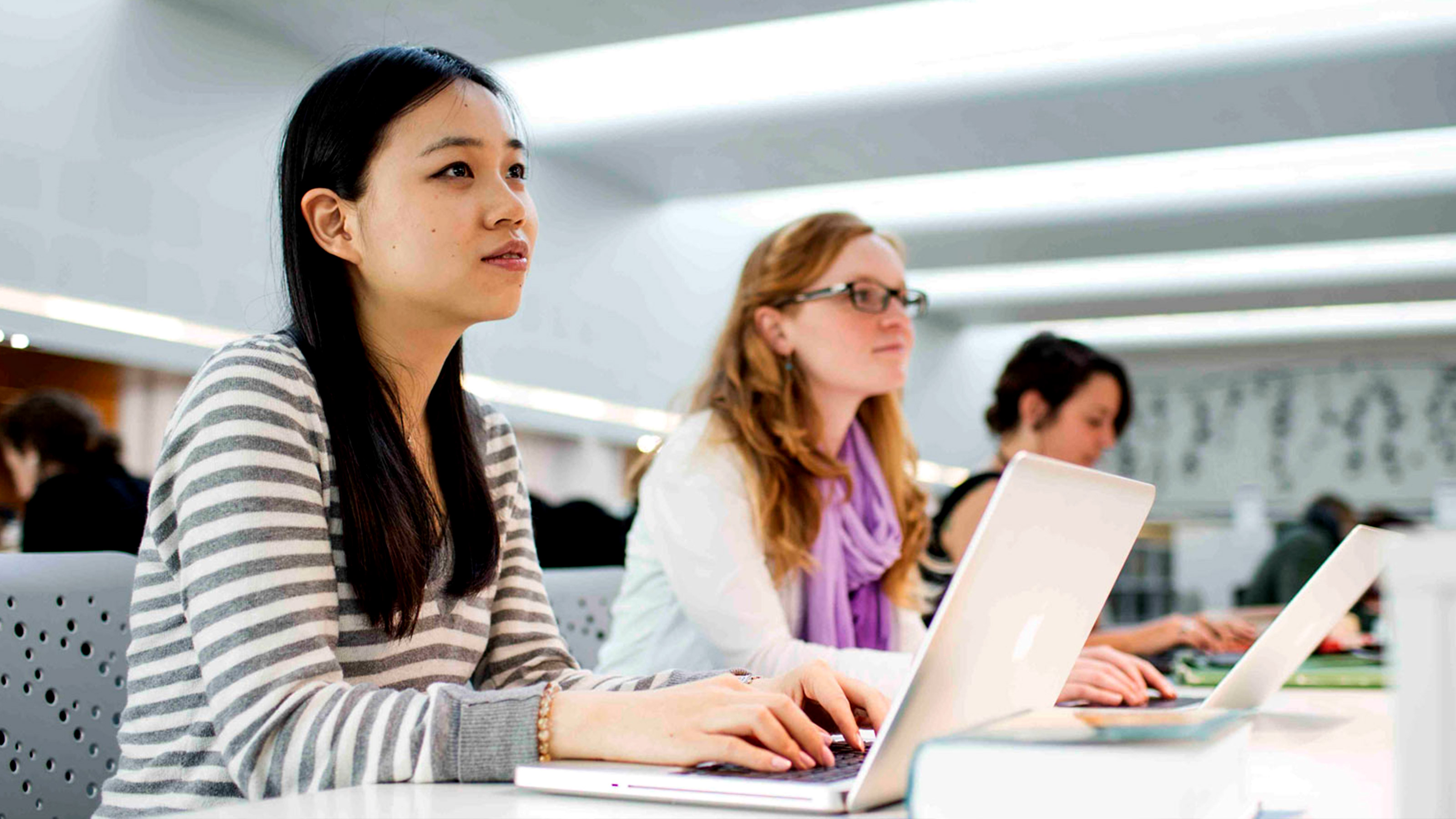 Students in class taking notes on laptops