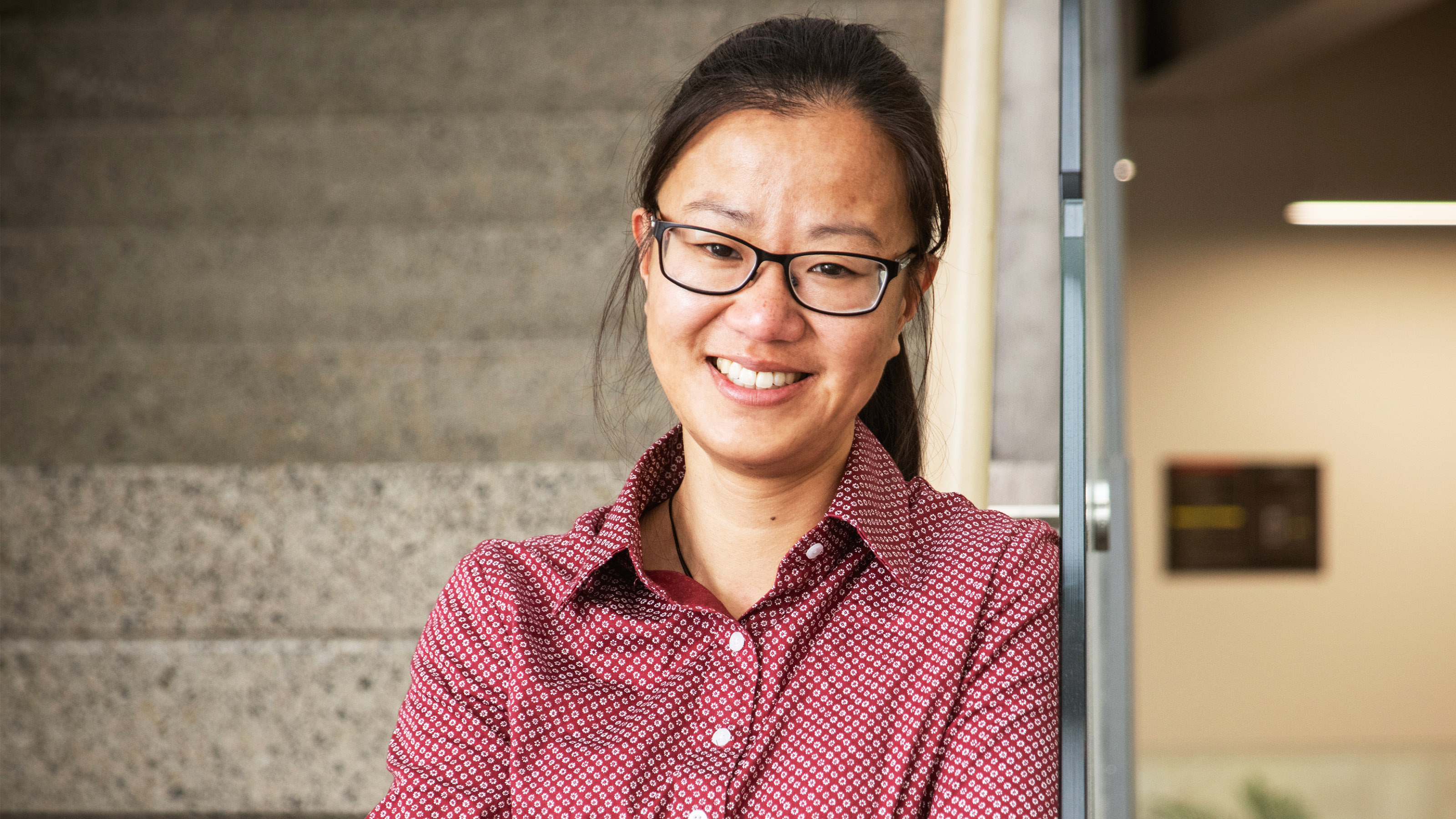 Jessica Lai stands beside an animation of honeycombs, bees and flowers.