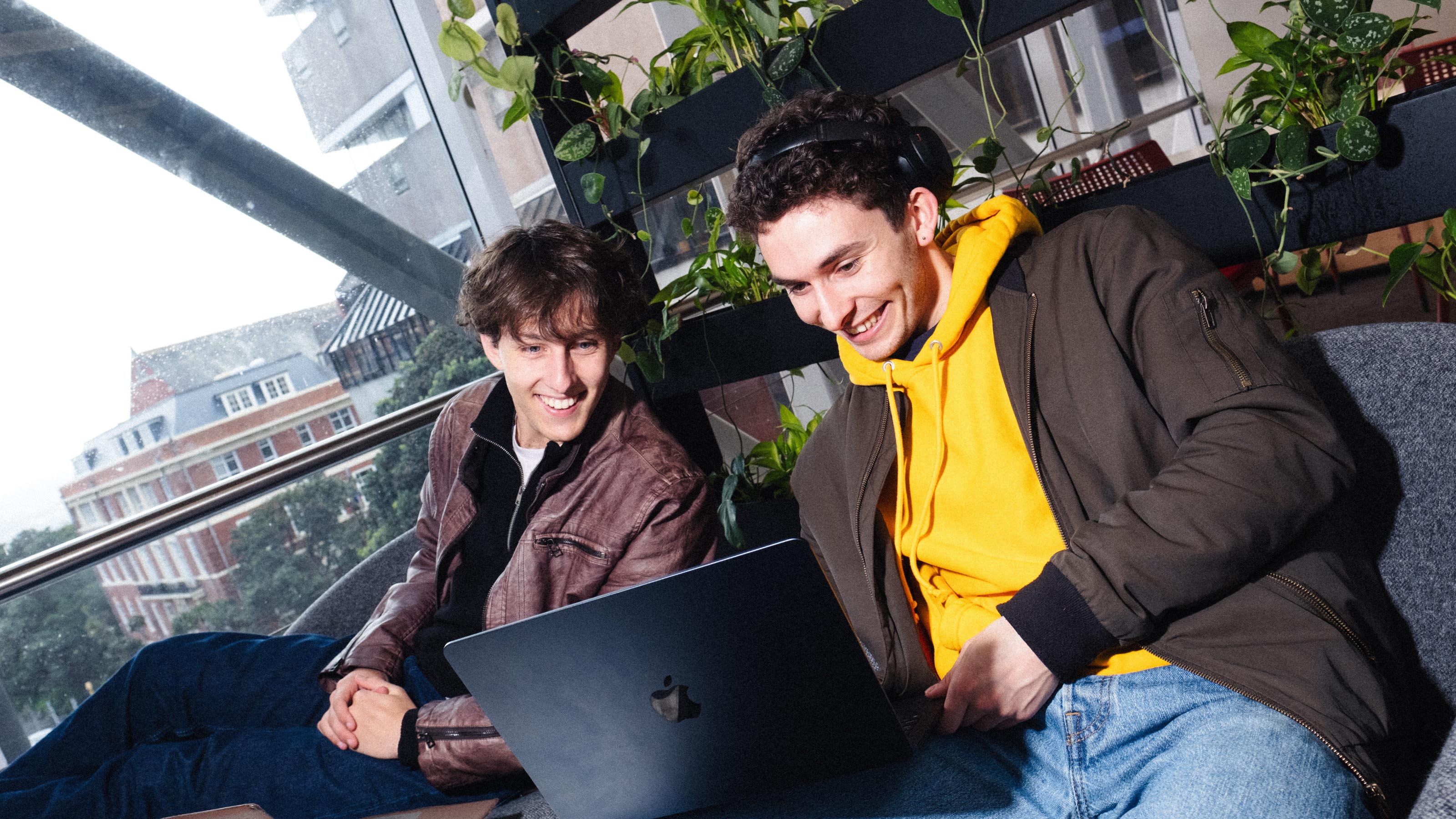 2 students on a couch looking at a laptop
