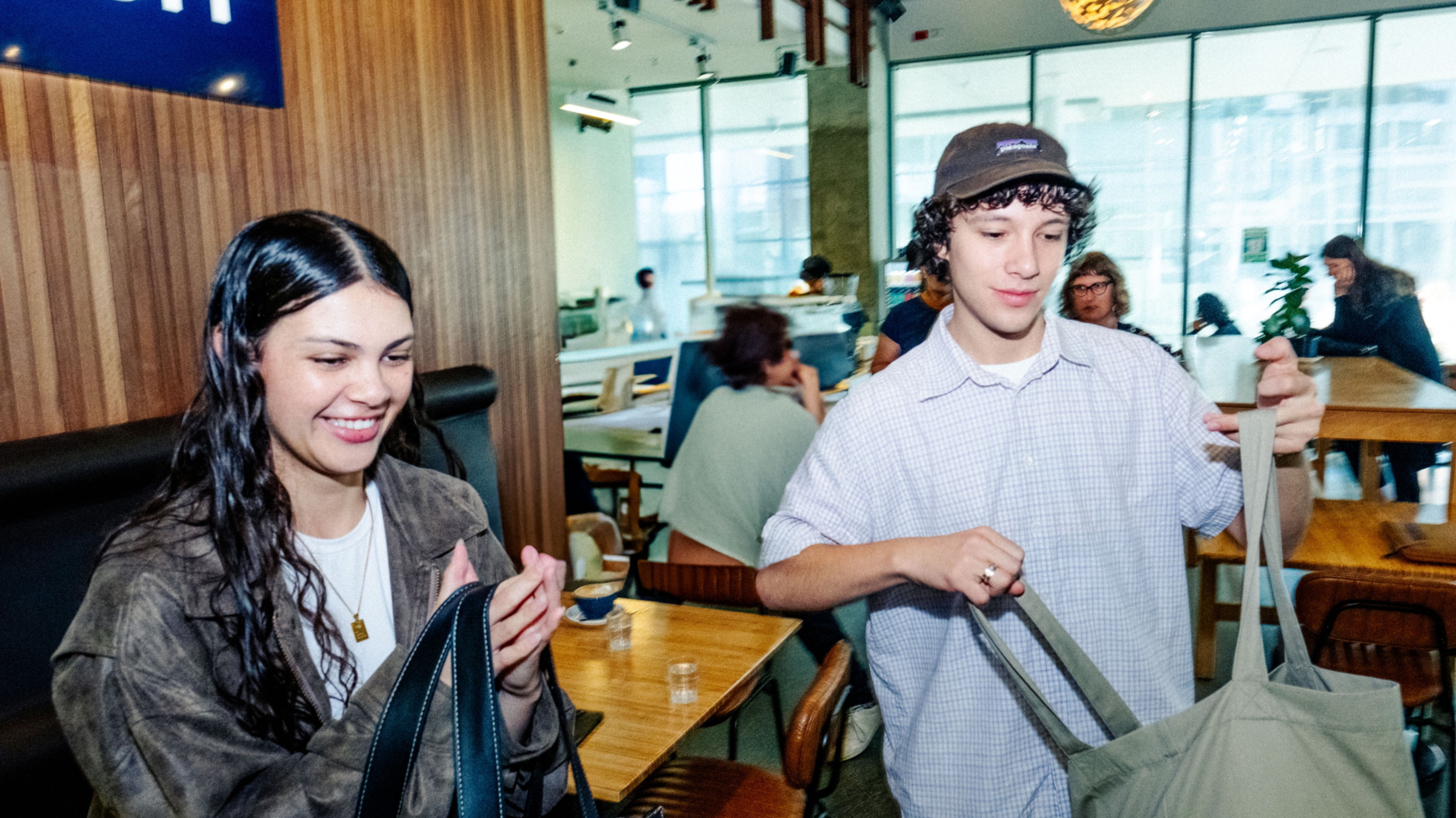 Two students grabbing their bags and leaving a cafe.
